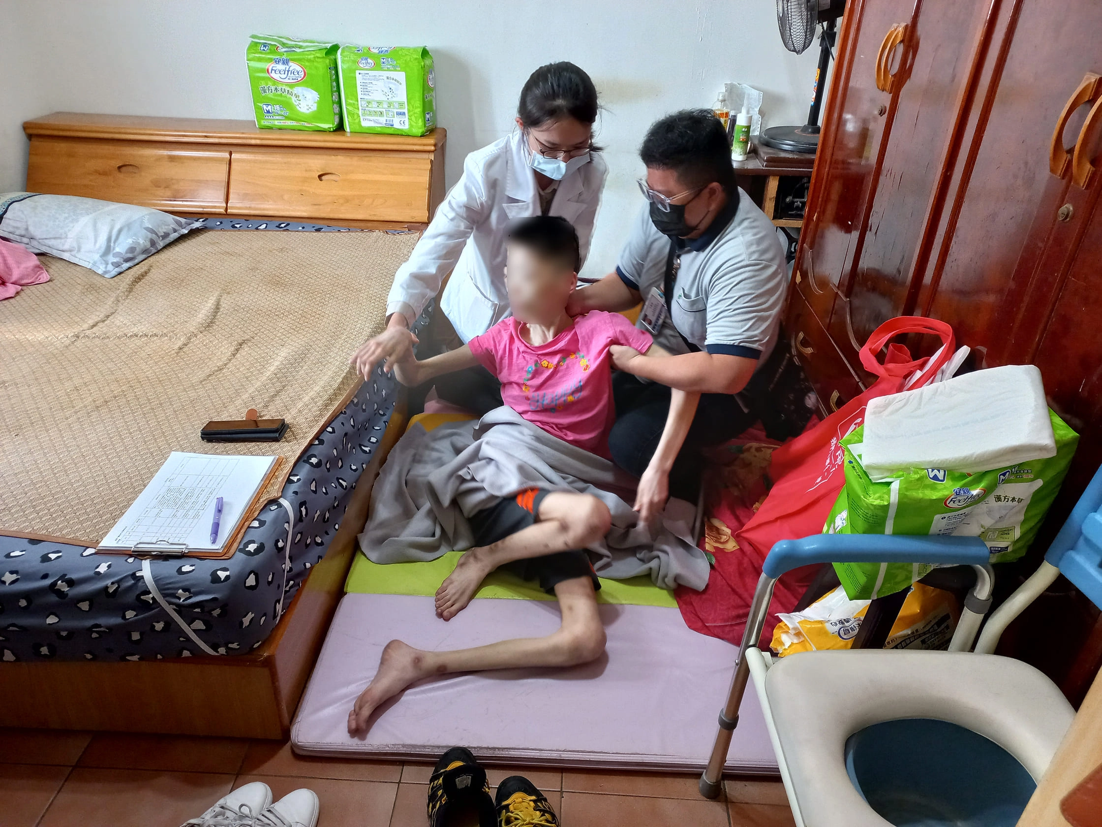 莊孟臻醫師（後）評估病人身體，建議用鼻胃管灌食，改善病人嗆咳問題。