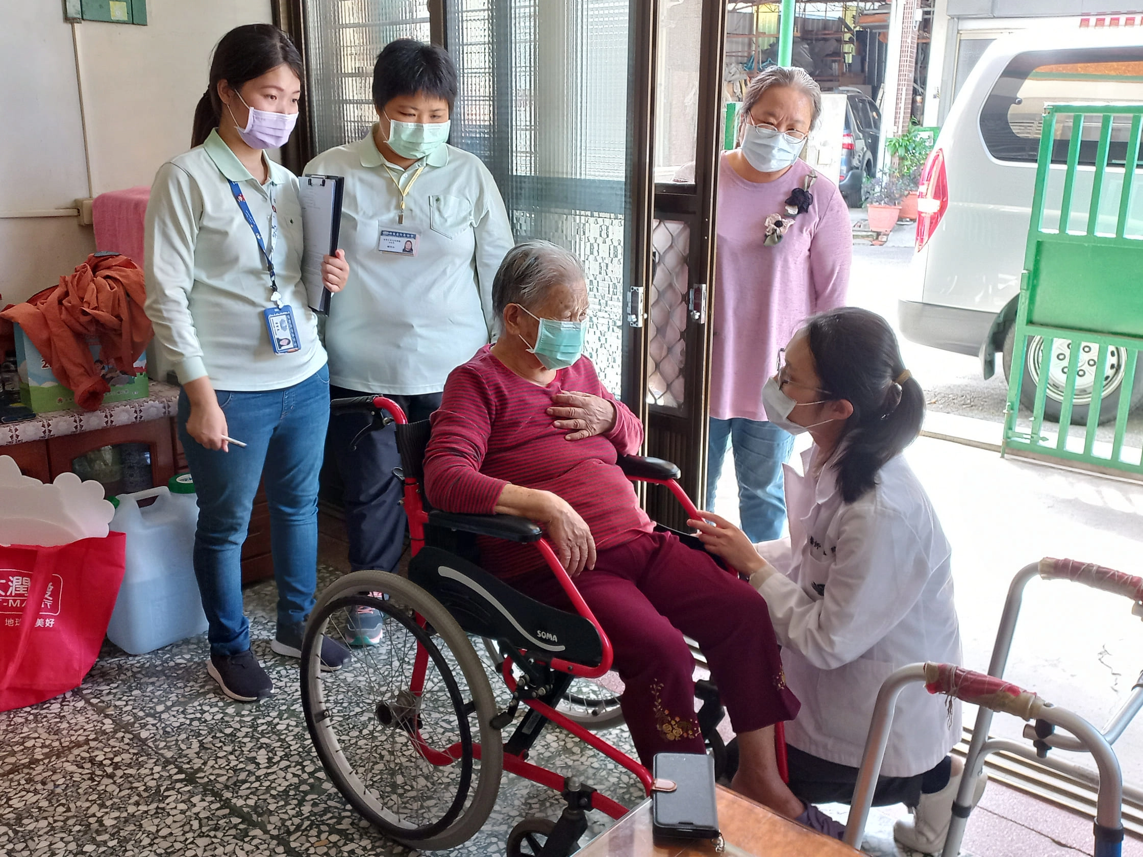莊孟臻醫師（右）蹲下關心往診長者健康。