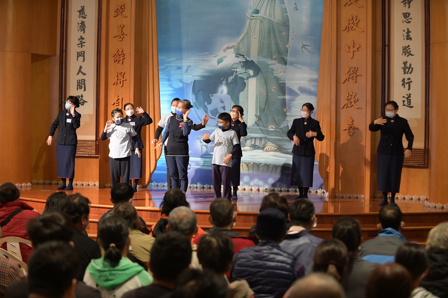 台東慈濟12月31日舉辦冬令發放活動，照顧戶侯女士與孫子上台表演手語。(攝影：陳信安)