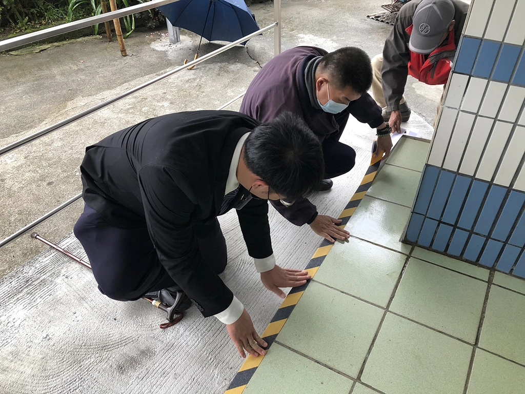 志工與社工在坡道上貼上止滑警示貼條。