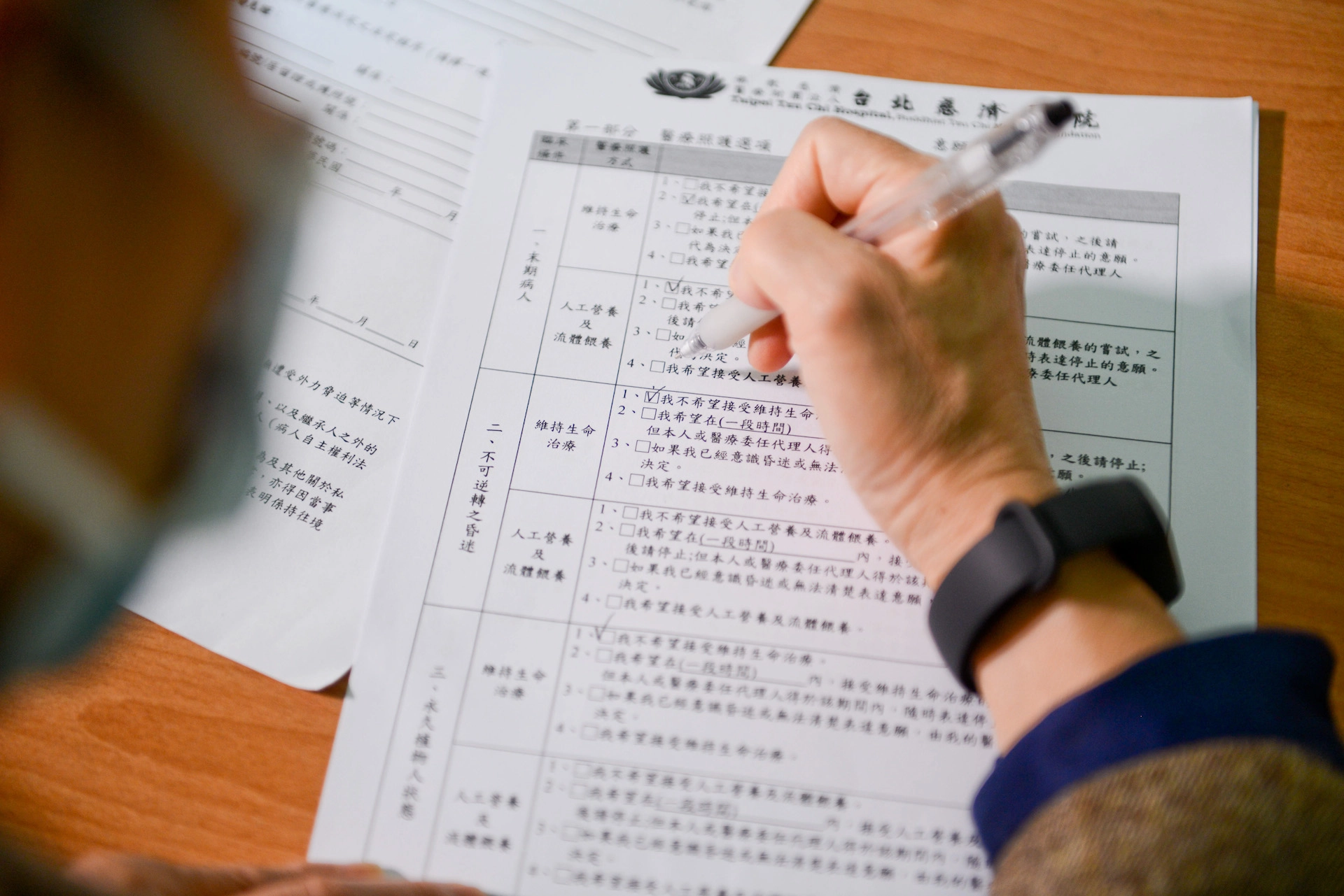 意願人與家人討論後，在預立醫療決定書上勾選自己期待的醫療選擇。