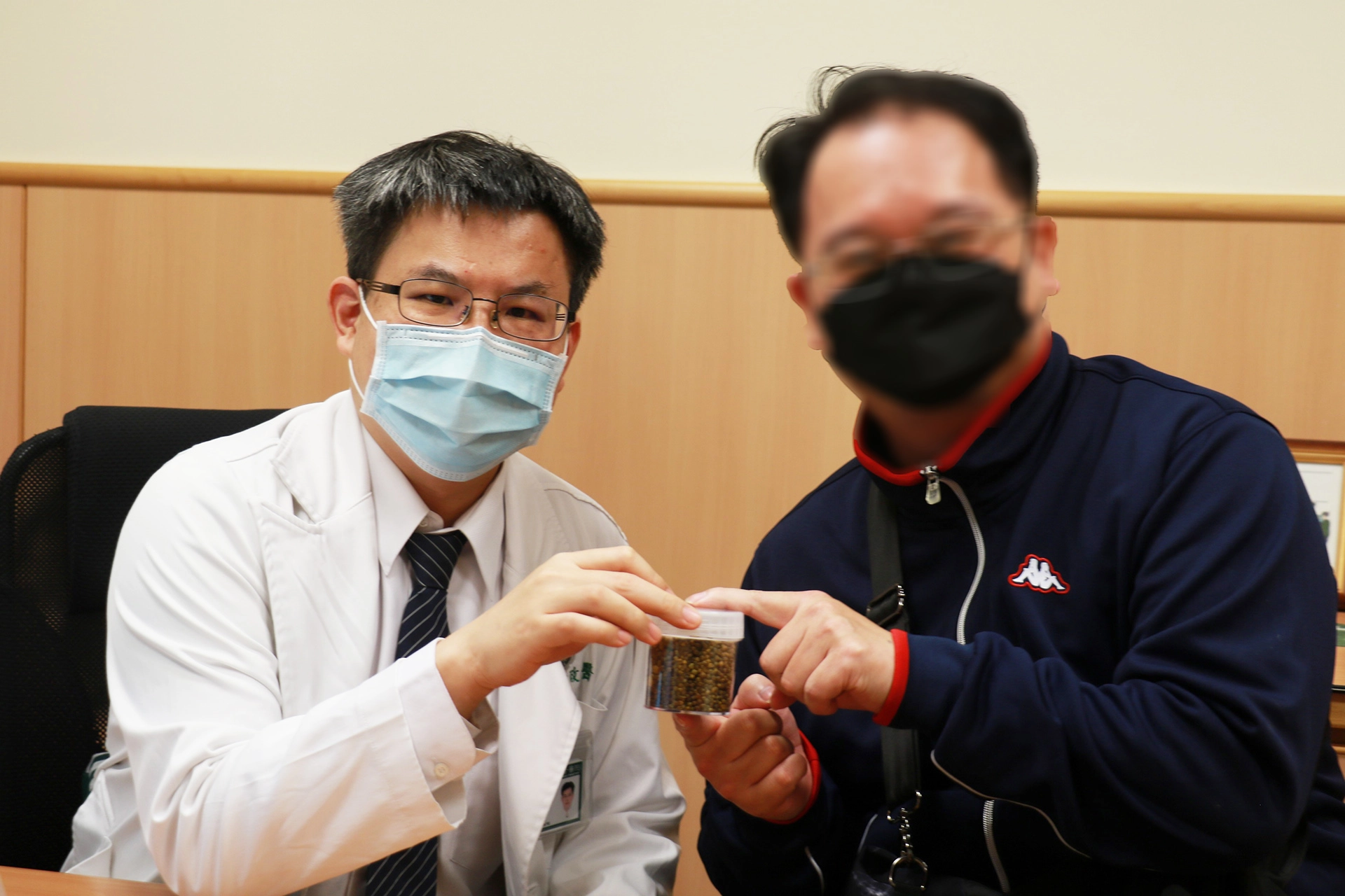 余政展主任（左）拿著膽囊取出的一整瓶膽結石，叮嚀回診病人清淡飲食保健康。