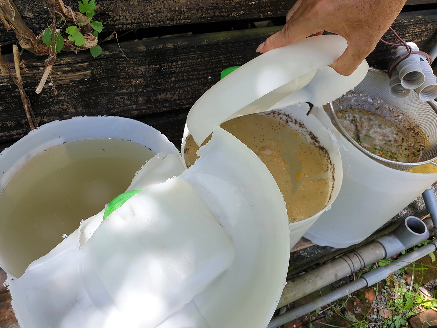 廚房的廢水裡有菜渣、有殘油等，利用三個水桶過濾進行「油水分離處理」再透過礫石中的滲透管流入土壤，再經土壤微生物分解後提供社區菜園作物所需的水與養份。
