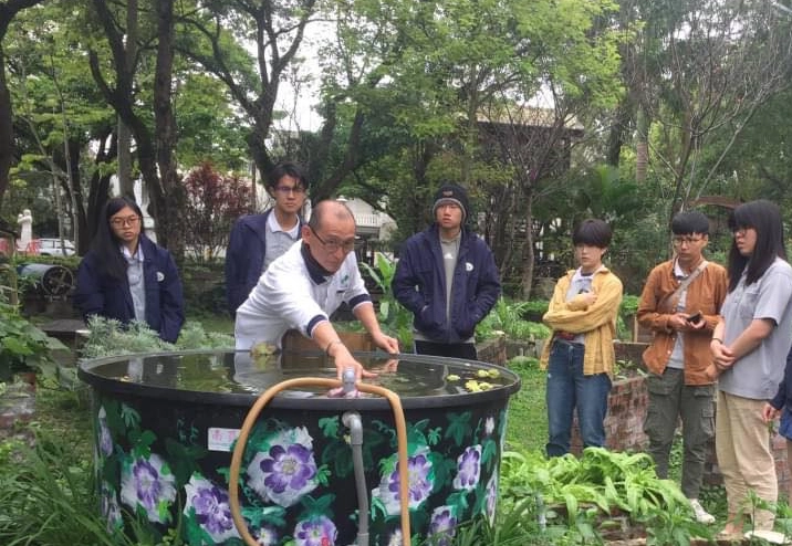 邱奕儒老師帶著學生了解魚菜共生菜園水池對菜園的幫助。