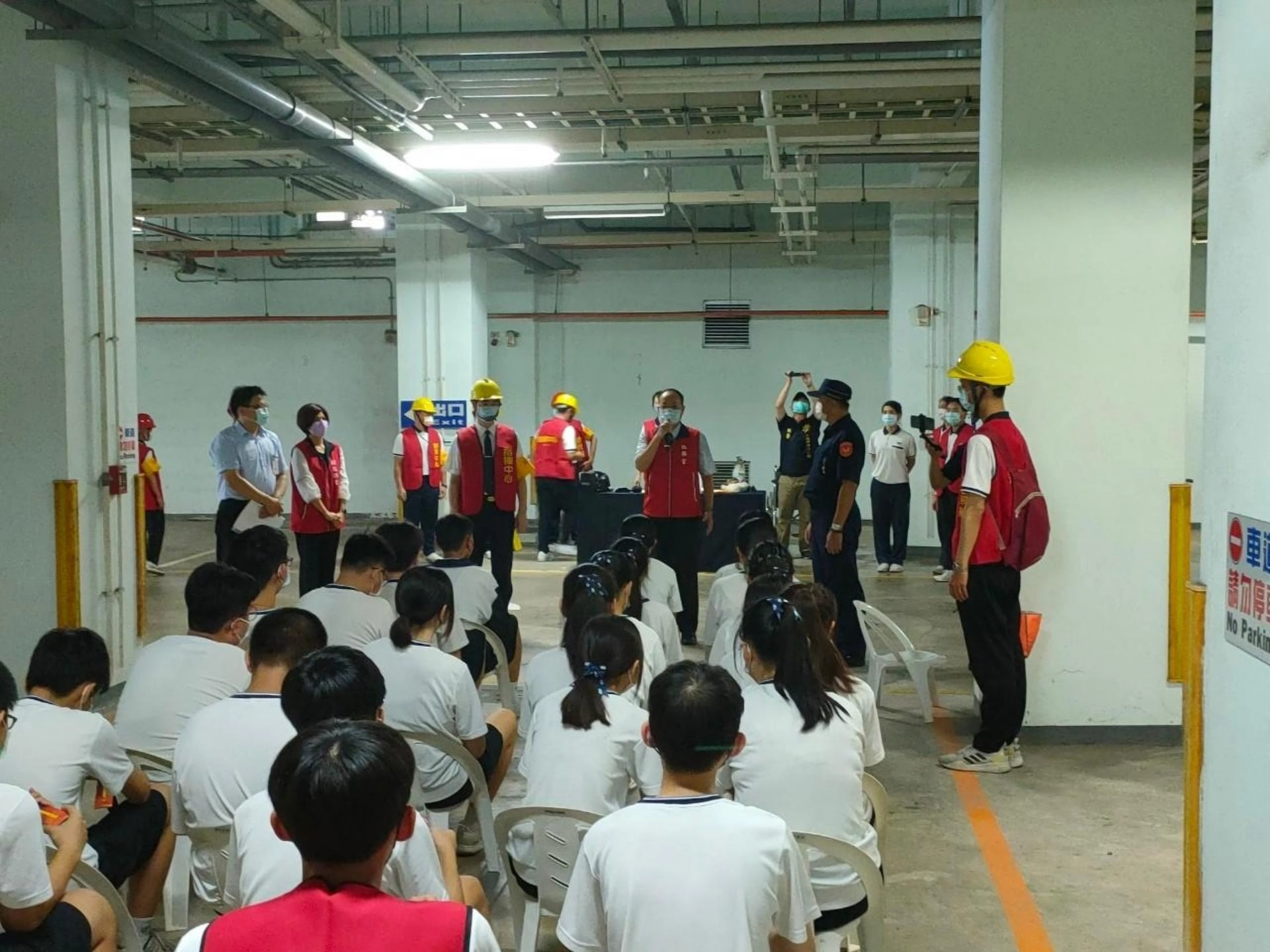 老師引導學生至地下停車場疏散避難區域，隨身攜帶班級防災避難包。