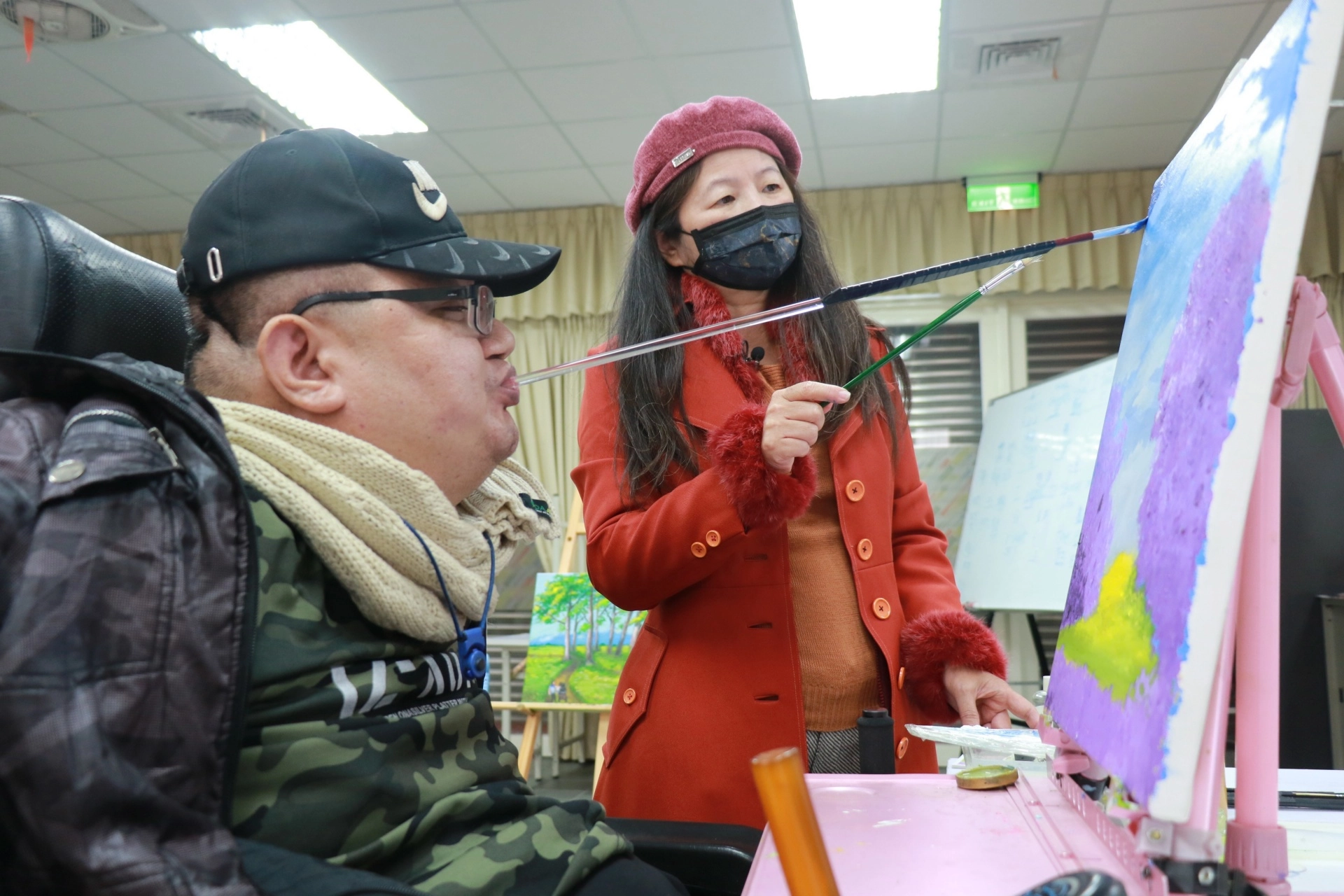 阮麗英老師(圖右)指導江永旭以口作畫。