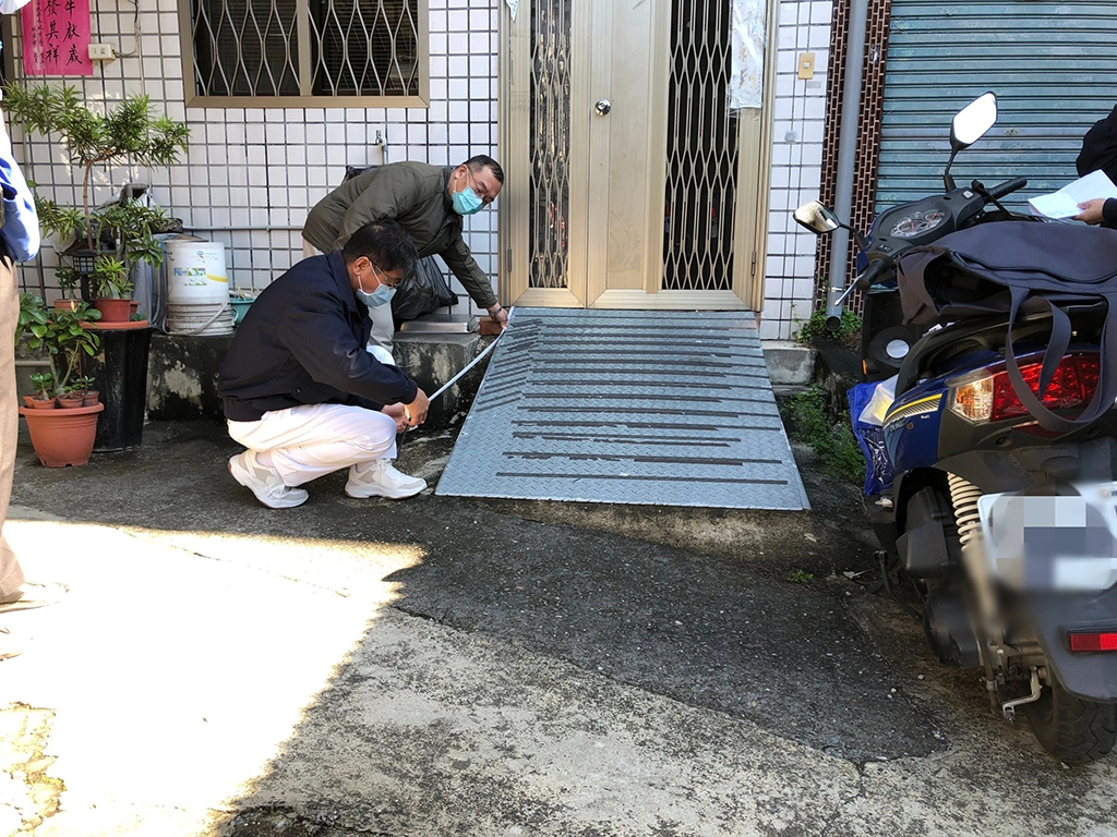志工為兩老相依長者門前斜坡道丈量要安裝防跌扶手尺寸。