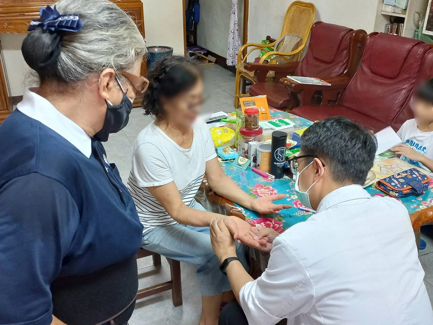 鄭主任透過望診察看手掌，瞭解往診鄉親身體狀況。