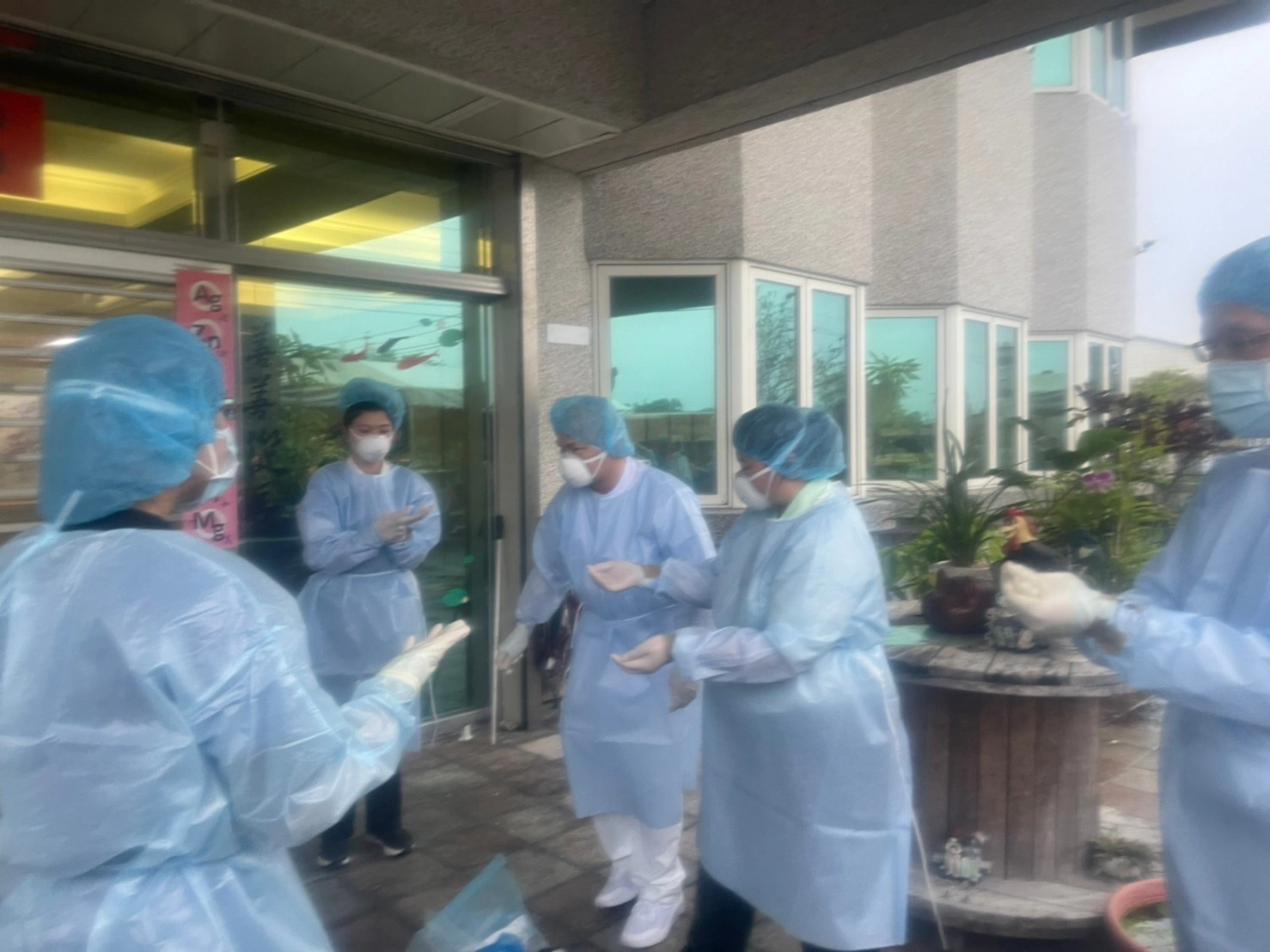 感管室黃妙慧主任（藍色工作服）、江惠莉組長（藍色工作服）、內科部副主任王智賢（後排右二）、老年醫學科主任高聖倫（後排右一）與社區健康中心護理師去安養中心做篩檢。