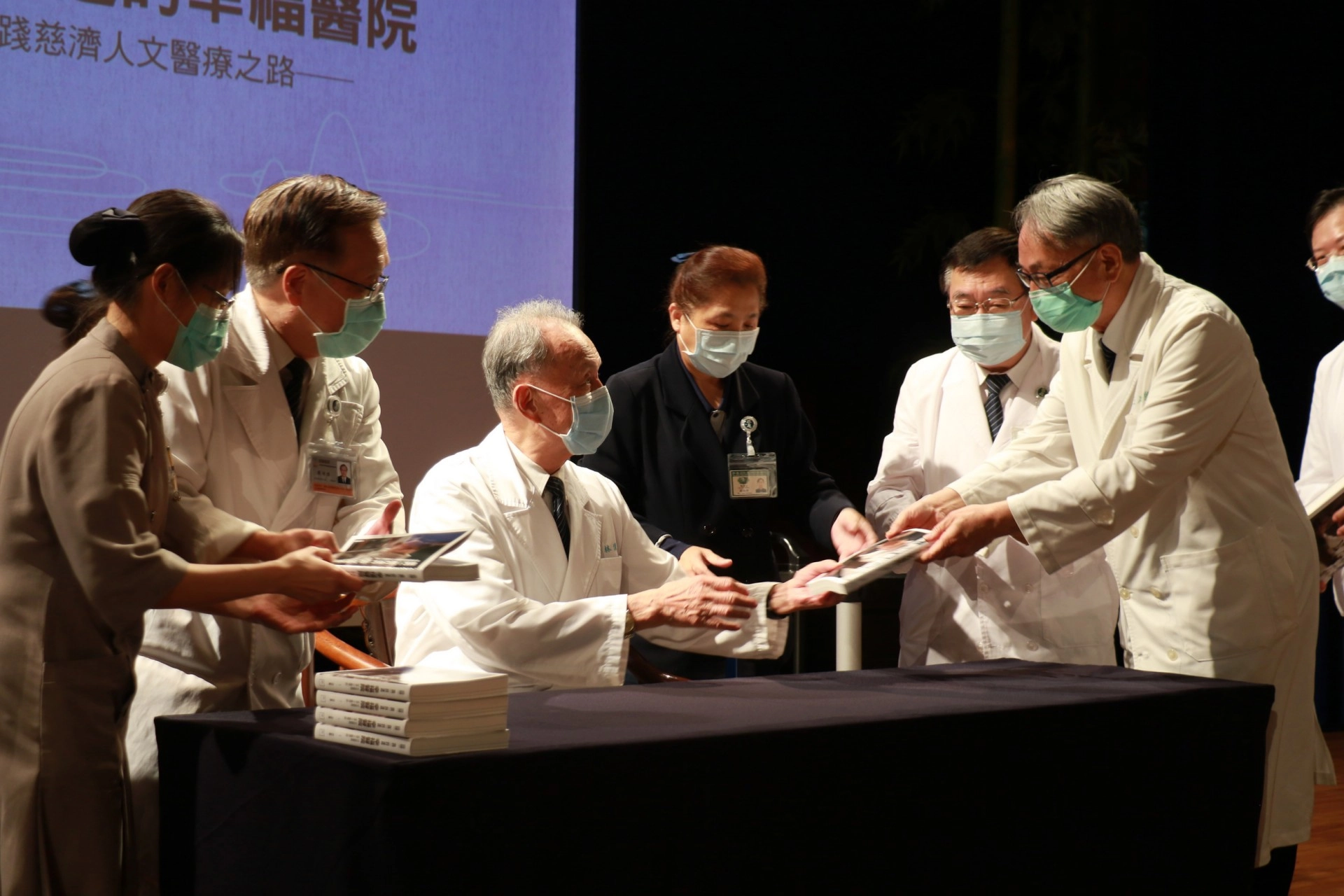 王人澍（右）、蔡顯揚（右二）兩位臺中慈院副院長，從林俊龍執行長手中拿到有簽名章的新書。