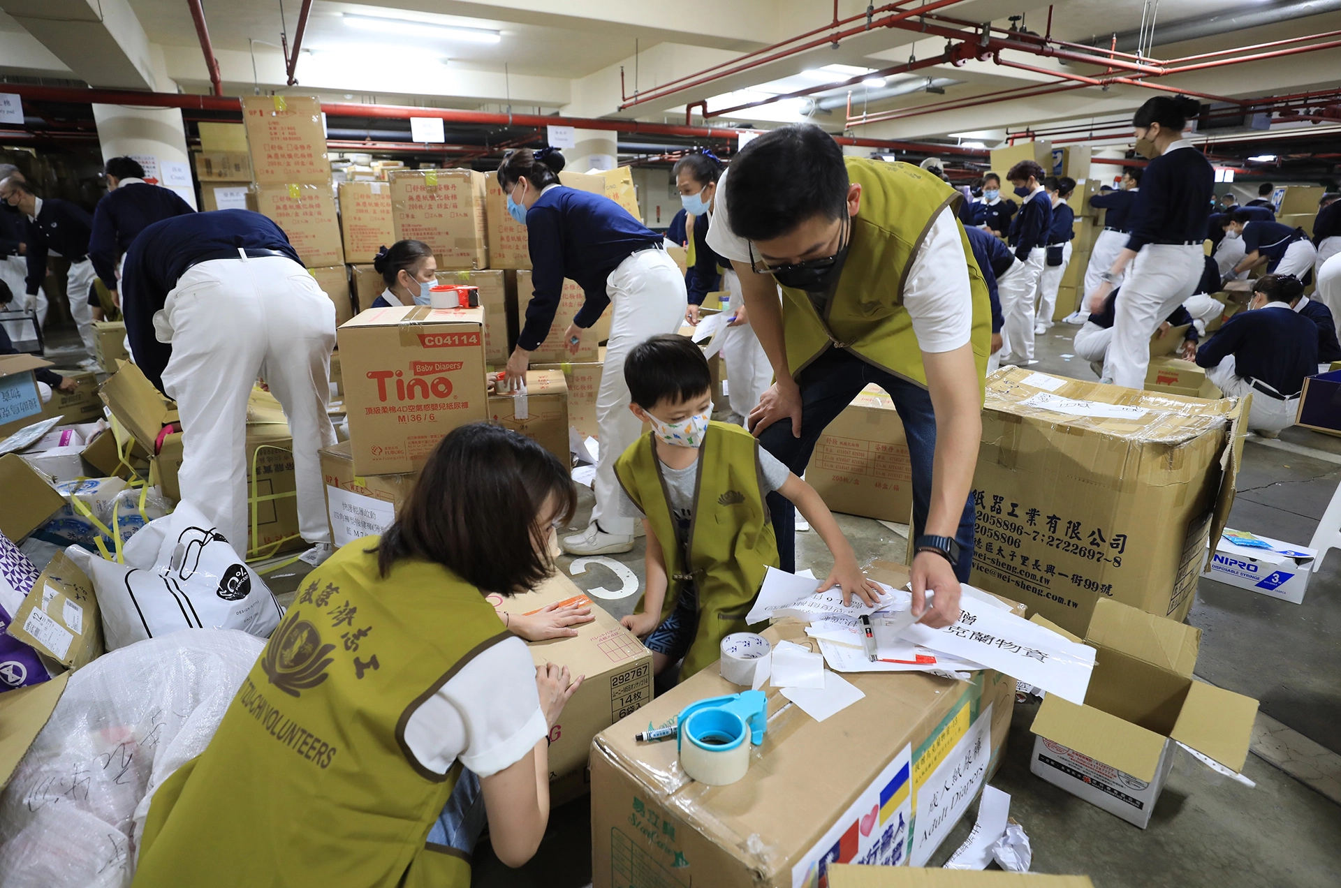 外交部援助烏克蘭難民物資打包現場有不少親子共善。