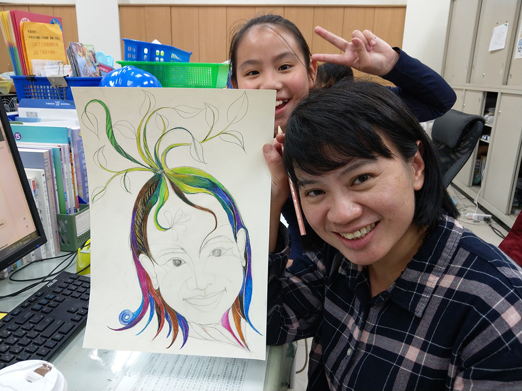 邱曉詩與學生合影，手上拿的是她的自畫像。