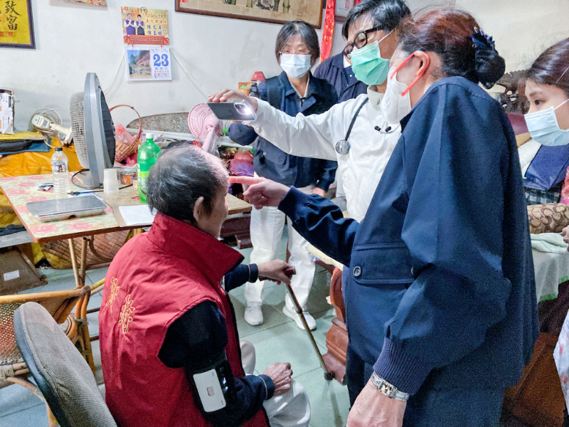 往診關懷上,林榮威醫師(法號:惟昶)以手機照明檢視阿公頭部傷口的癒合情形。