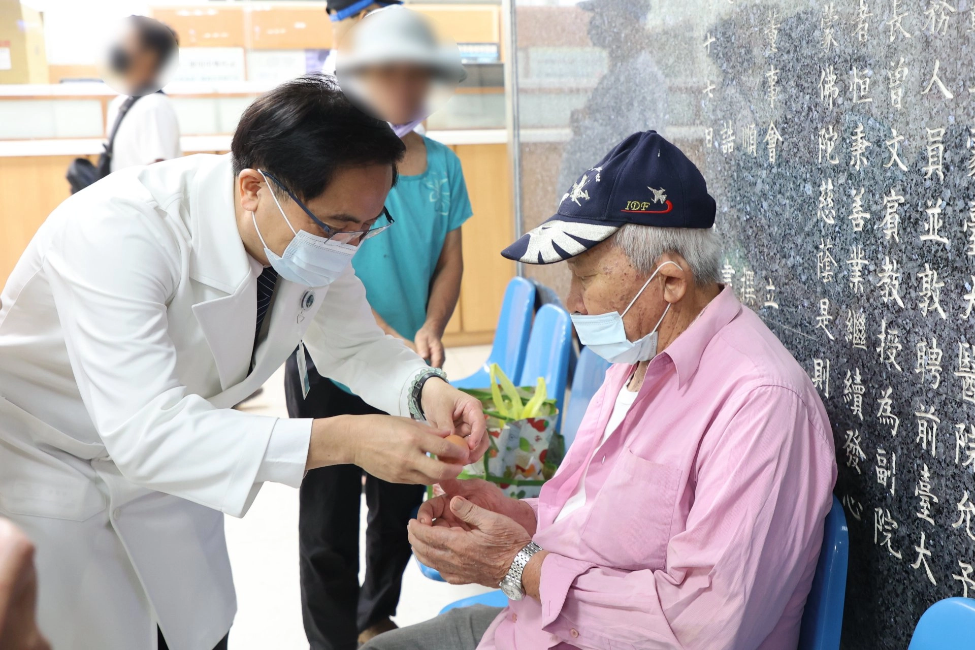 志工室主任顏靜曦也準備了喜氣洋洋的紅蛋，由林欣榮院長、醫務秘書李毅代表，在大廳與病人及家屬分享院慶喜悅。