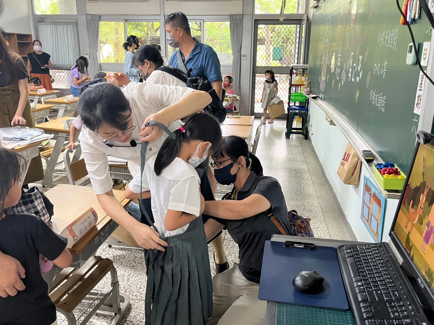 老師與家長一同為孩子套量制服。