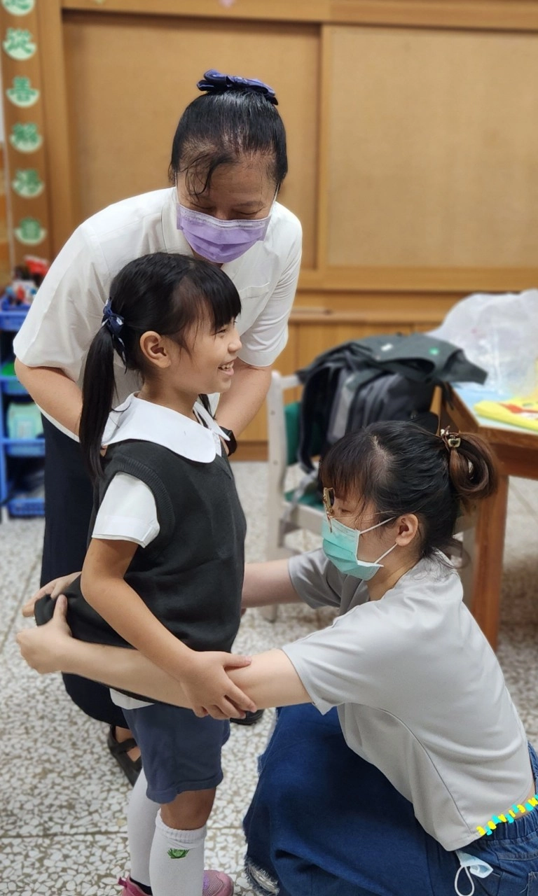老師與家長一同為孩子套量制服。
