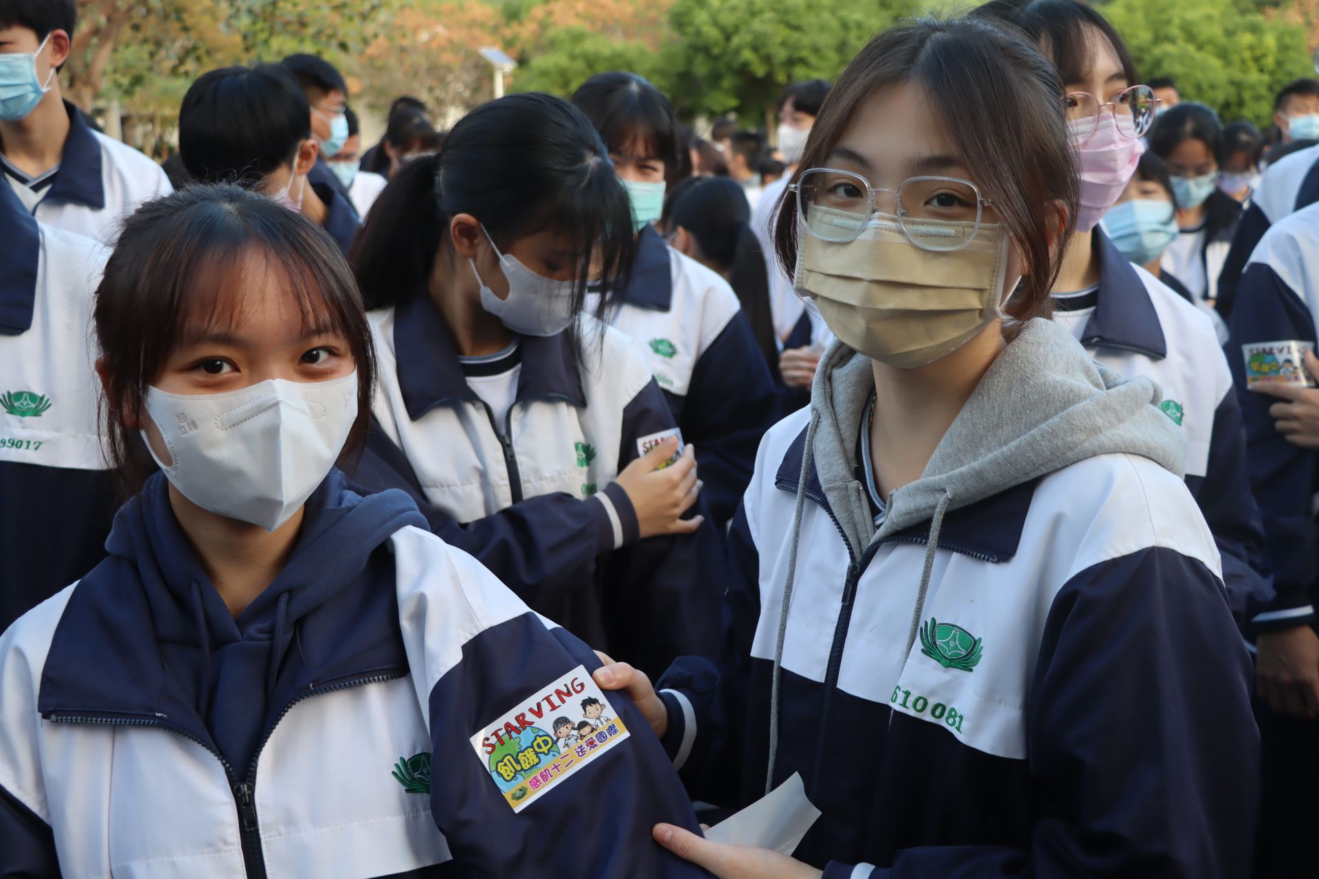 參與感飢活動的學生們為彼此貼上「飢餓中」貼紙，將自己省下的餐費捐助興建滿納海