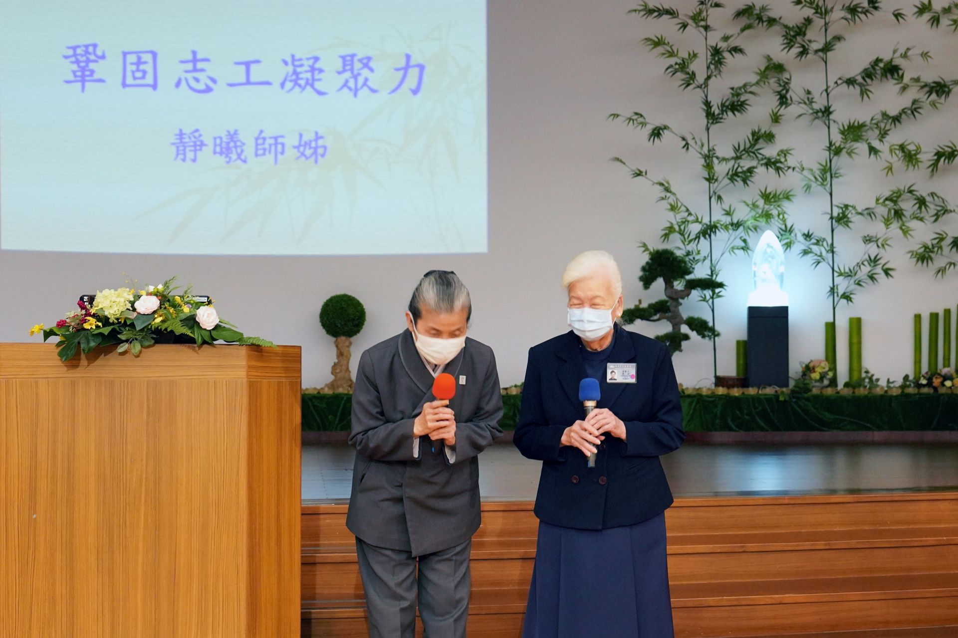 顏靜曦師姊(左)跟李節子師姊一走到台前就深深一鞠躬，感恩醫療志工全年無休付出。<br/>李節子師姊(右)叮嚀，做領隊最重要訣竅就是「不能給人家看臉色」。