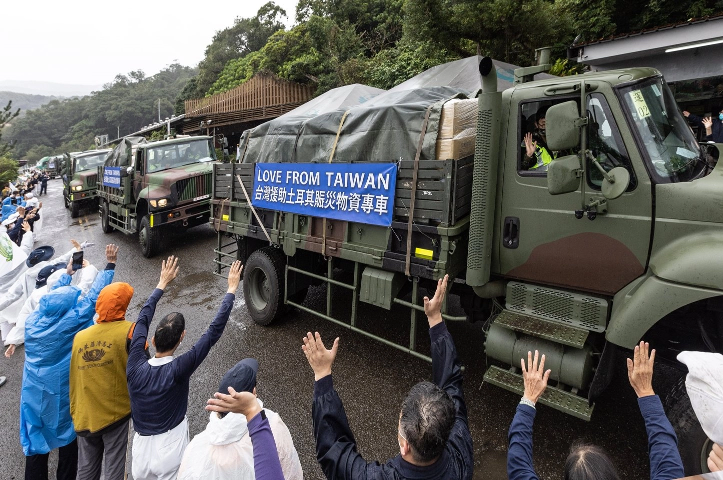 志工及民眾向國軍載運土耳其賑災物資車隊揮手致意。