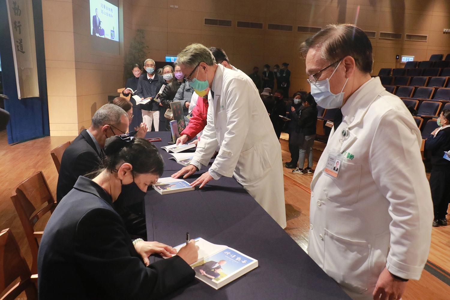 簡守信院長（右一）、王人澍副院長（右二）率先讓書中主角及作者簽名。