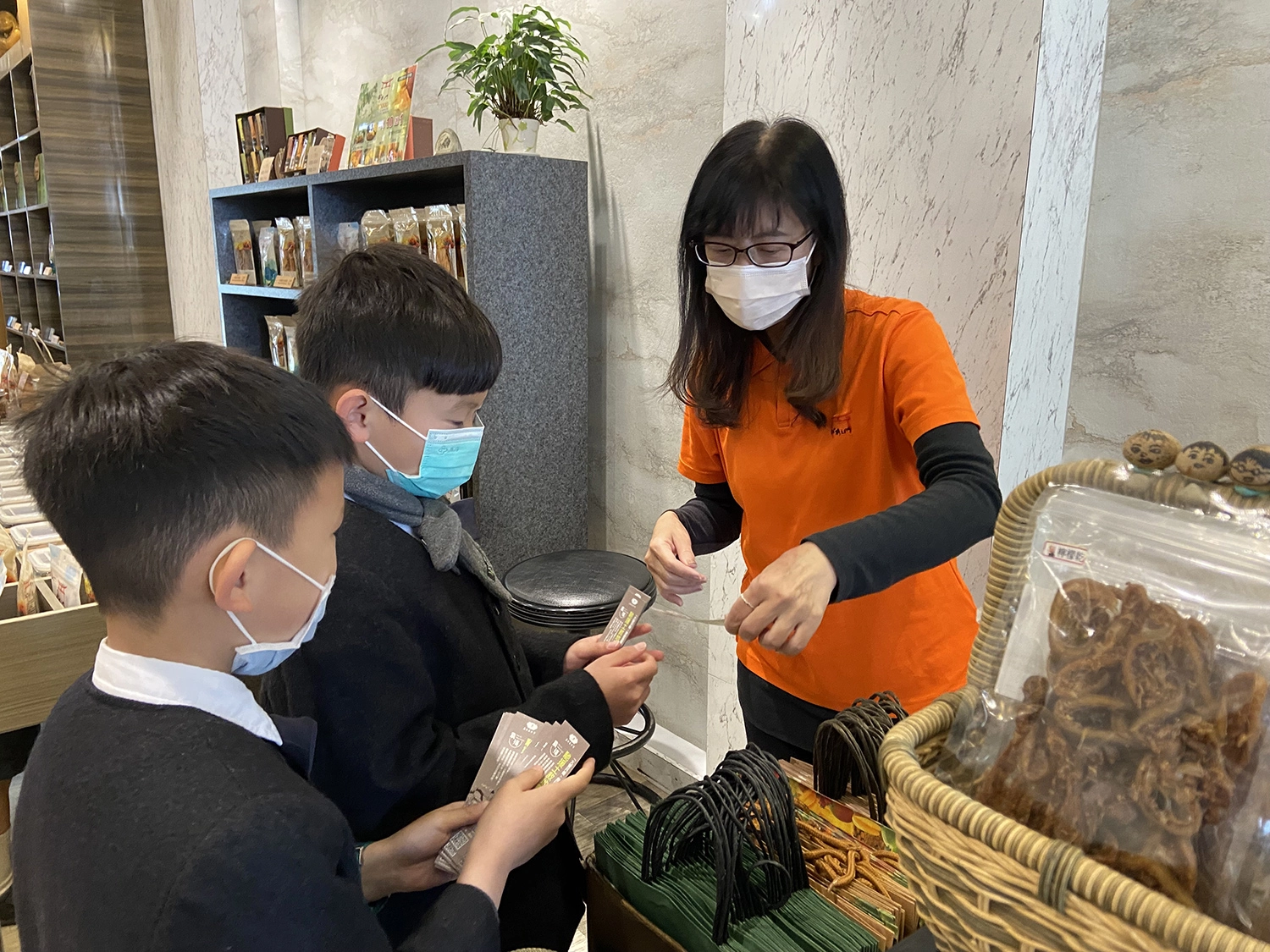 彬彬有禮的國小吳宥澄(圖中)及周信叡(圖左)向店家說明土敘地震援助的訊息。（林昱汝攝影）