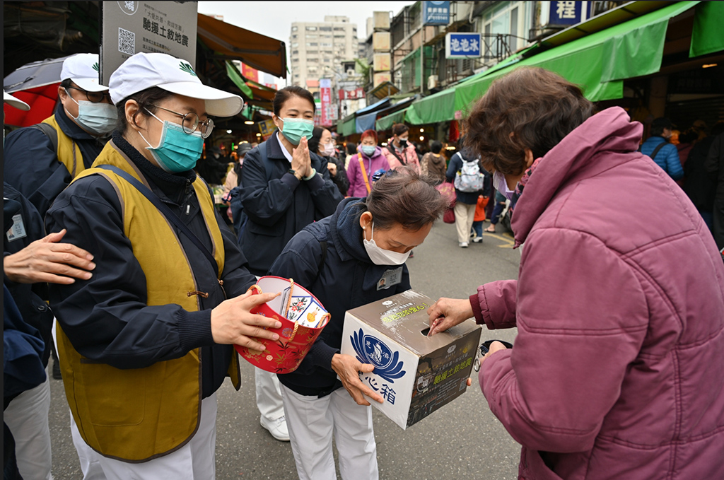 人潮熱鬧的南京東路五段二九一巷菜市場，像是拜訪老朋友似的，經過許多菜販、水果攤、等貨攤志工打招呼募心也募款。 