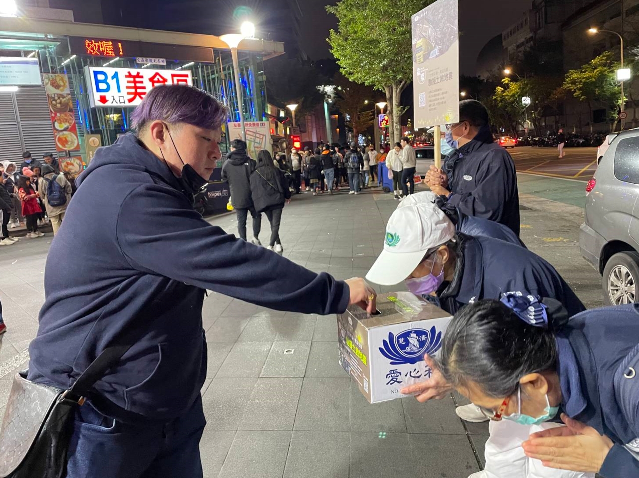 志工手捧愛心箱頂著寒風晚上在人潮聚集的士林夜市募心募愛。