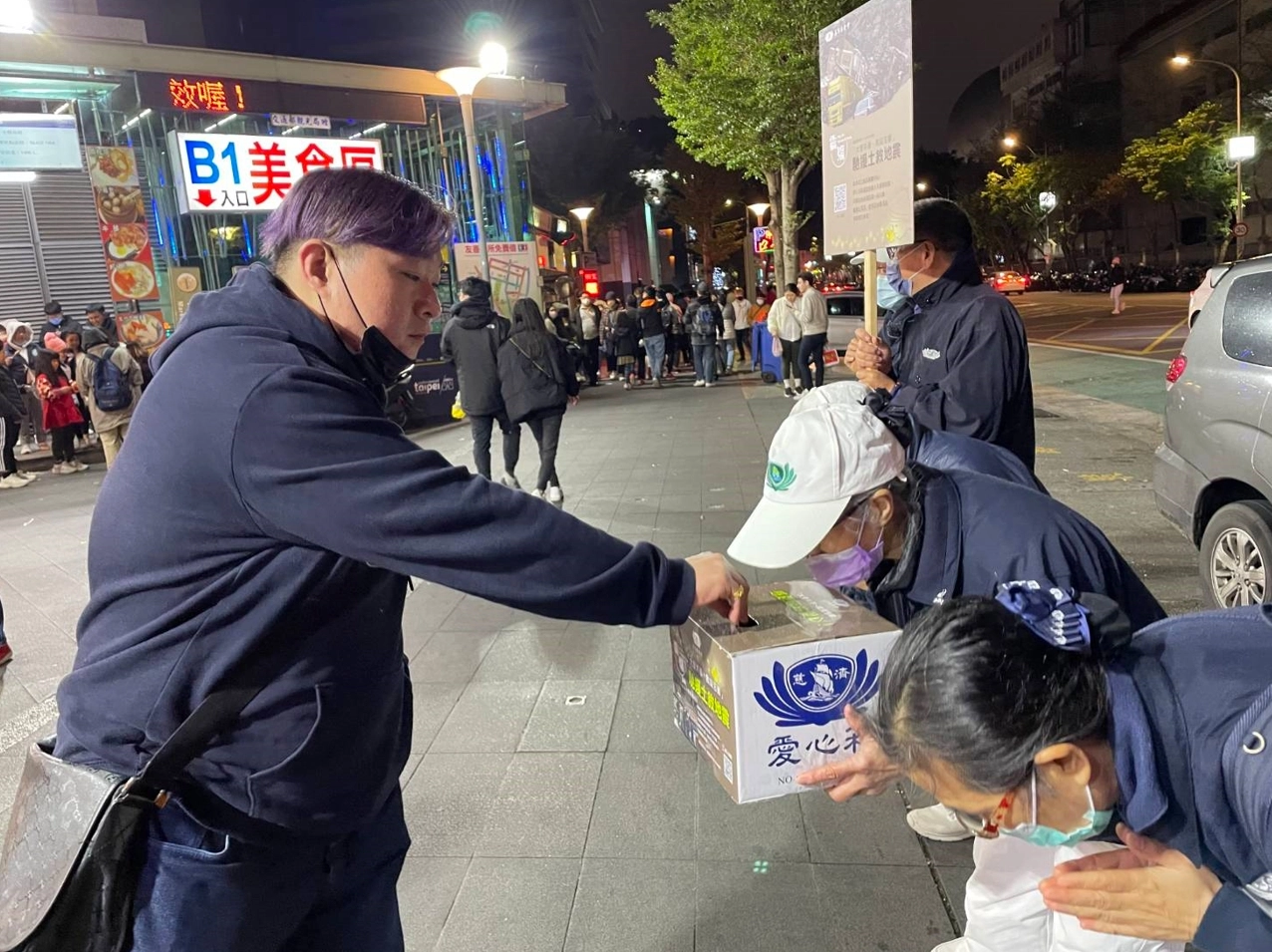 志工手捧愛心箱頂著寒風晚上在人潮聚集的士林夜市募心募愛。