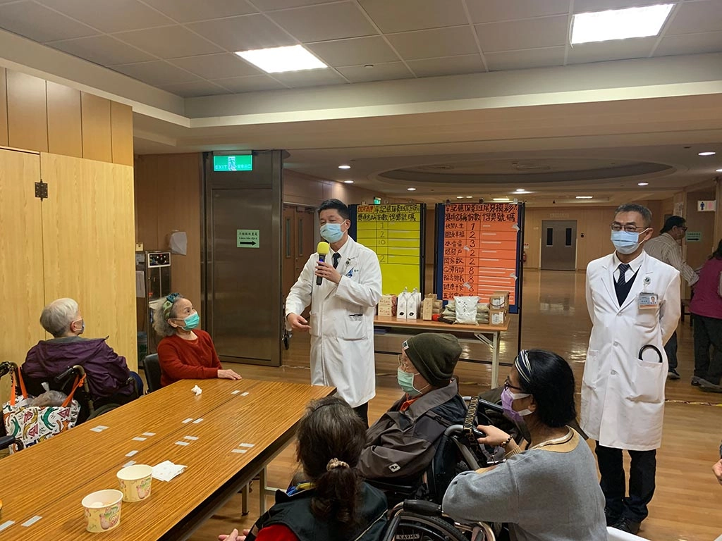社區健康中心主任陳慶元（左）、神經內科醫師傅進華（右）來與長輩摸彩、切蛋糕同歡。