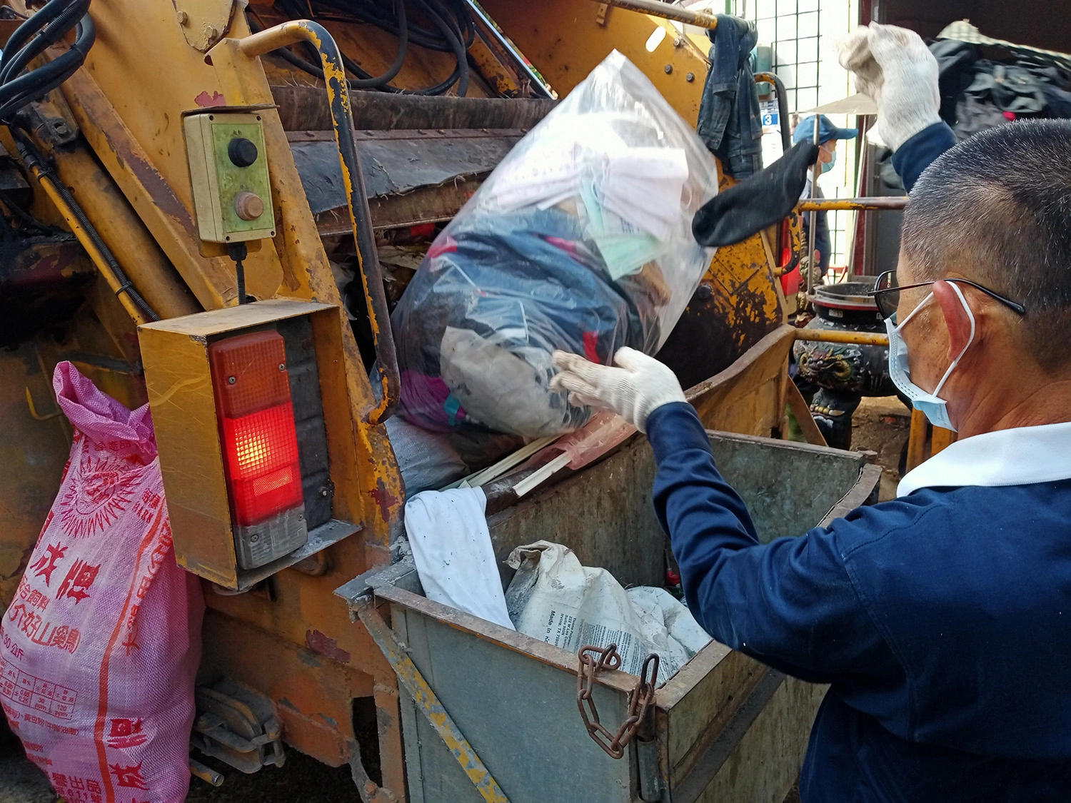 志工將垃圾送上公所清潔隊回收車運回處理。