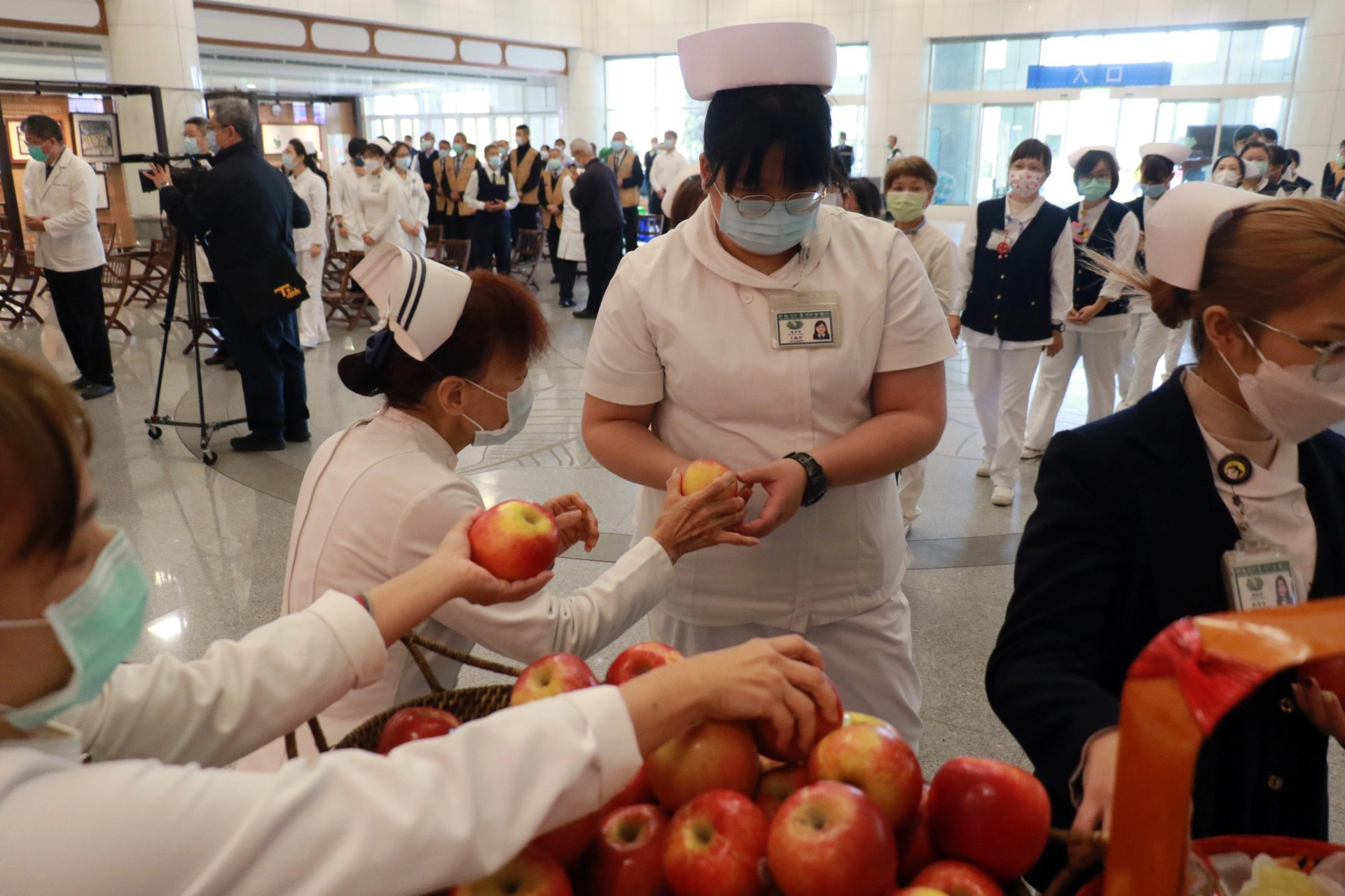 臺中慈濟醫院護理部主任張梅芳（左）發送象徵「平安」的蘋果，祝福同仁。