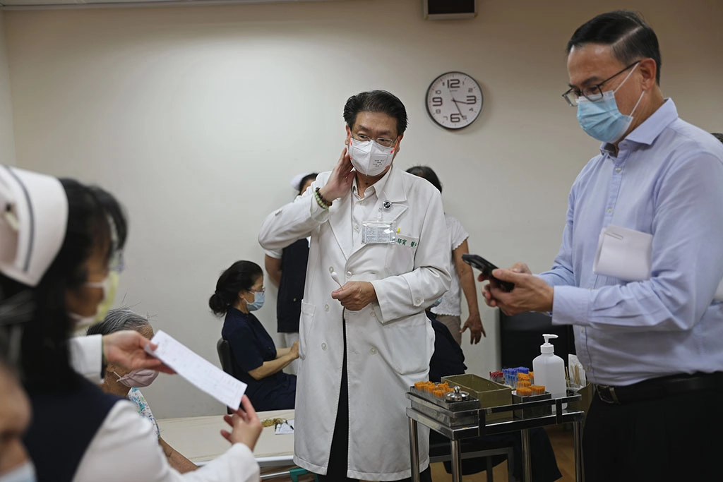 張俰賓博士與新加坡慈濟基金會主管至花蓮慈院中醫門診，觀摩中醫部針灸科主任林郁甯為患者針灸治療，並用手機拍照記錄細節。