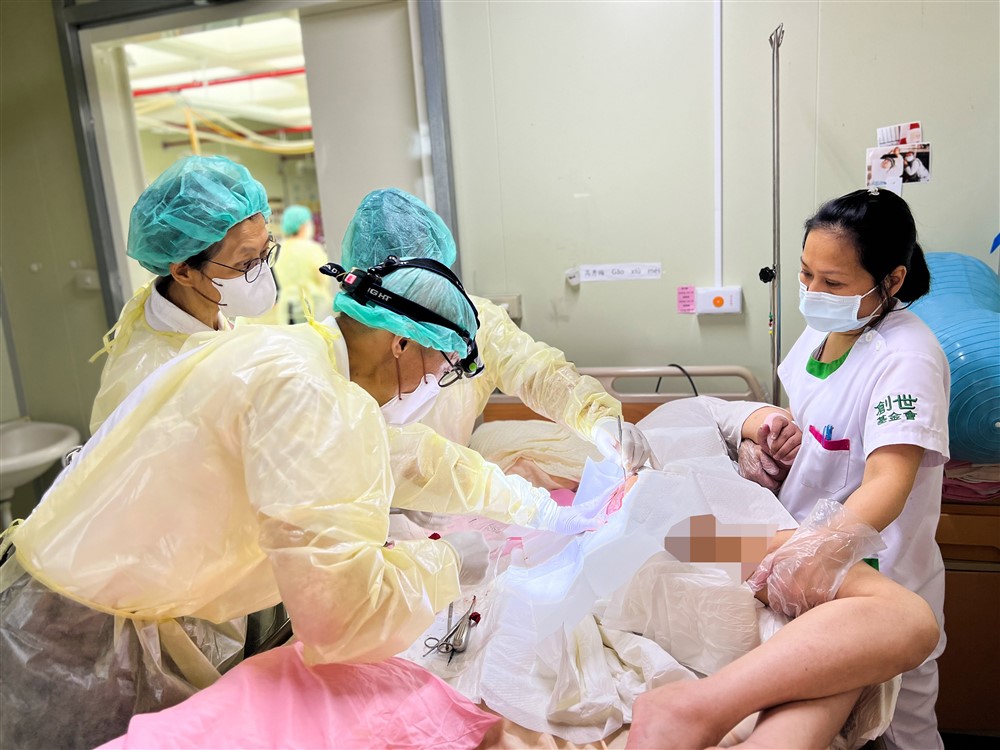 葉添浩醫師（左前）仔細為褥瘡病人進行傷口清創。太太陳紅燕藥師（左一）與護理師一起從旁協助。