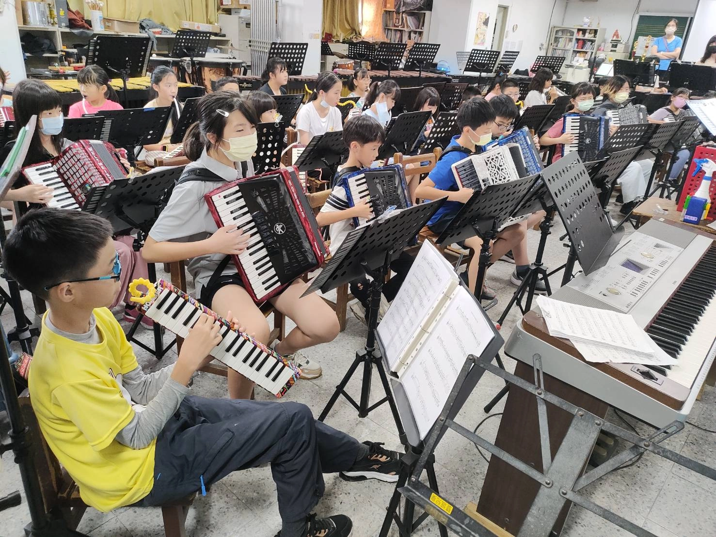 黃色上衣的是林大耕、拉手風的是吳若瑜跟林大㠭，三人剛好坐在一起。