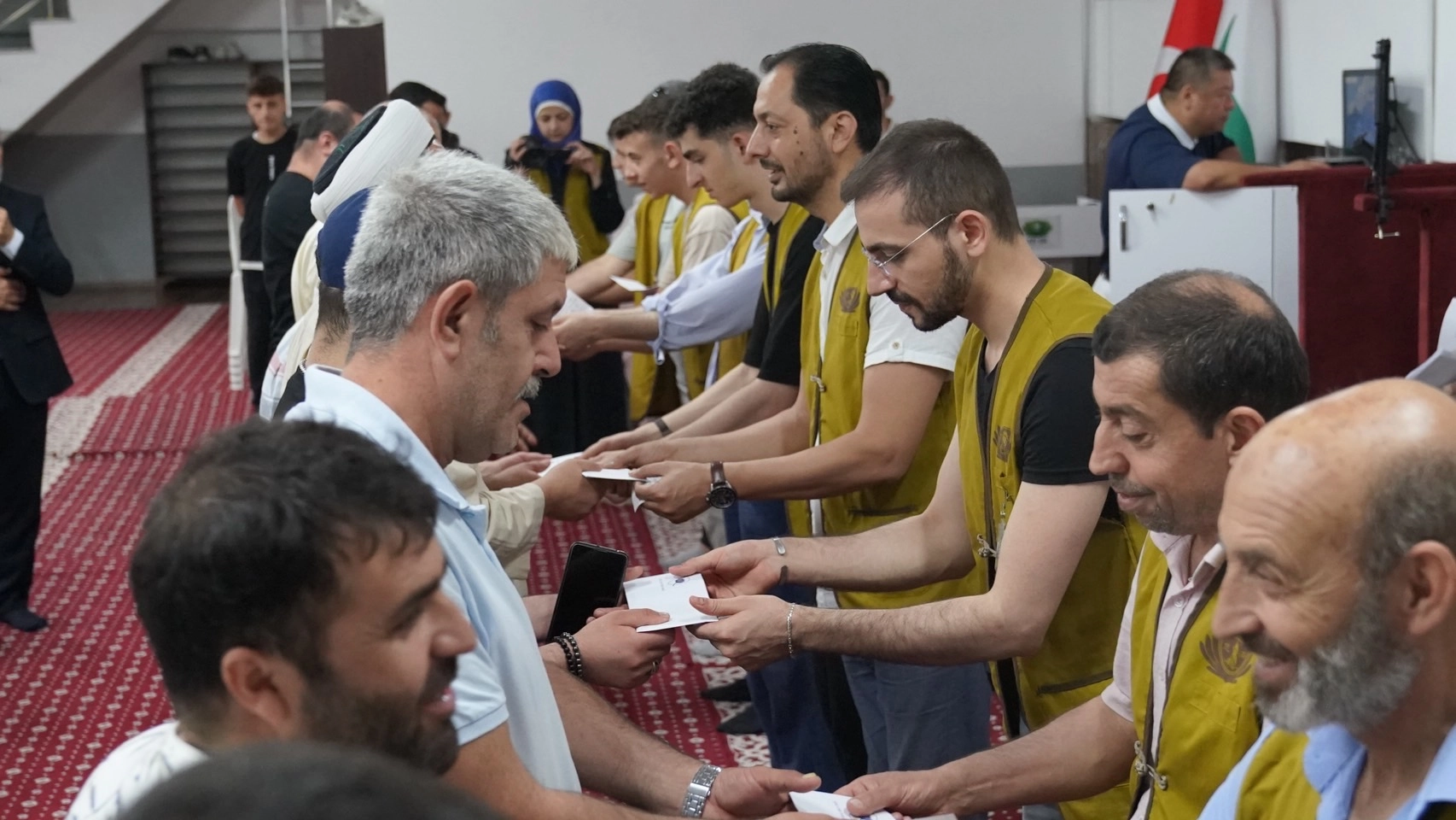 土耳其慈濟7月22日舉辦2場關懷戶發放活動，志工雙手發放購物卡。