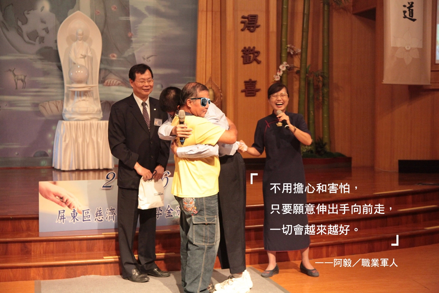 阿毅（左三）感恩大伯（左二）養育之恩，給予一個溫馨的擁抱。圖為2016年慈濟新芽獎學金頒獎現場。