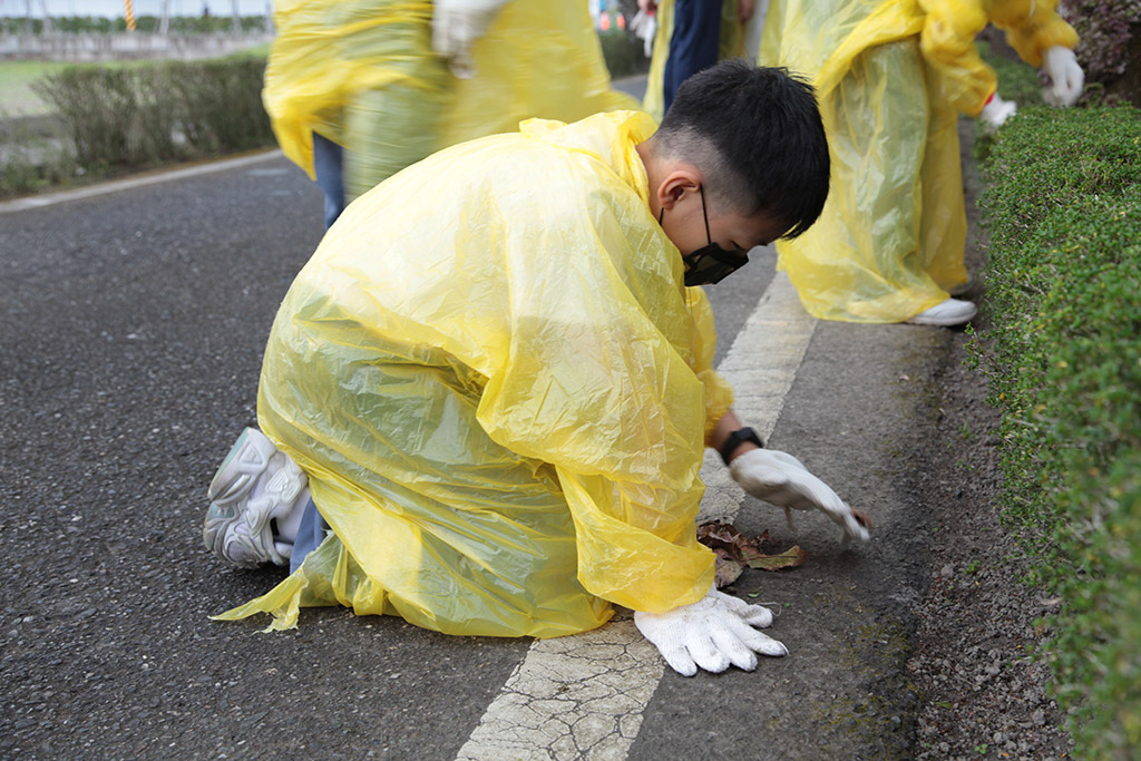 即使下著小雨，學生仍專著輕便雨衣蹲著身子細心撿拾。