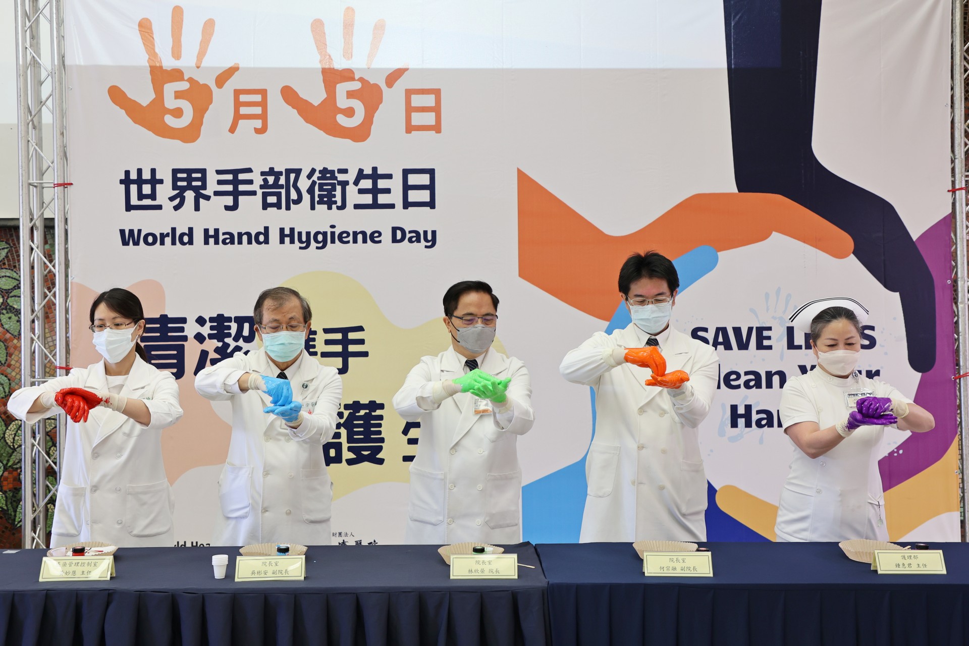 左起感控室主任黃妙慧、副院長吳彬安、院長林欣榮、副院長何宗融、護理部主任鍾惠君，以顏料示範正確洗手7步驟(內、外、夾、弓、大、立、腕)。
