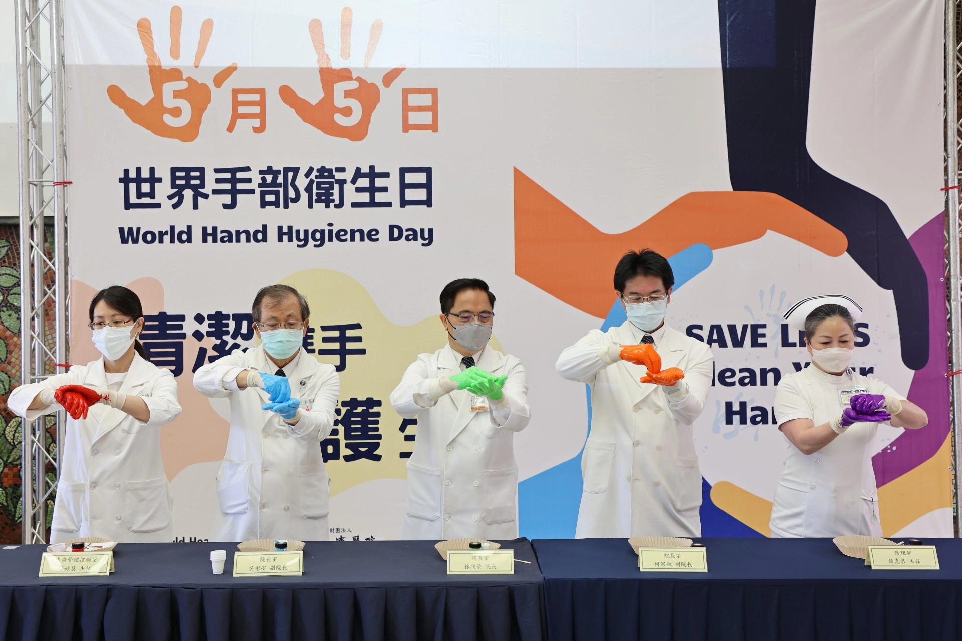 左起感控室主任黃妙慧、副院長吳彬安、院長林欣榮、副院長何宗融、護理部主任鍾惠君，以顏料示範正確洗手7步驟(內、外、夾、弓、大、立、腕)。