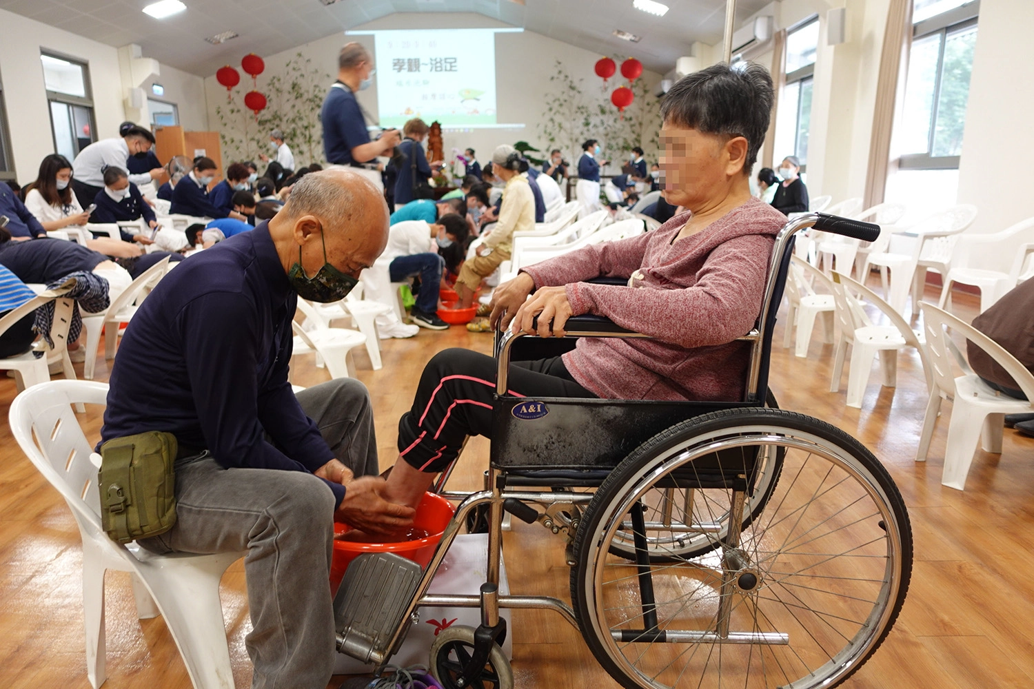 羅先生(左一)幫腦傷妻子洗腳按摩多年，參加浴足活動祈福。