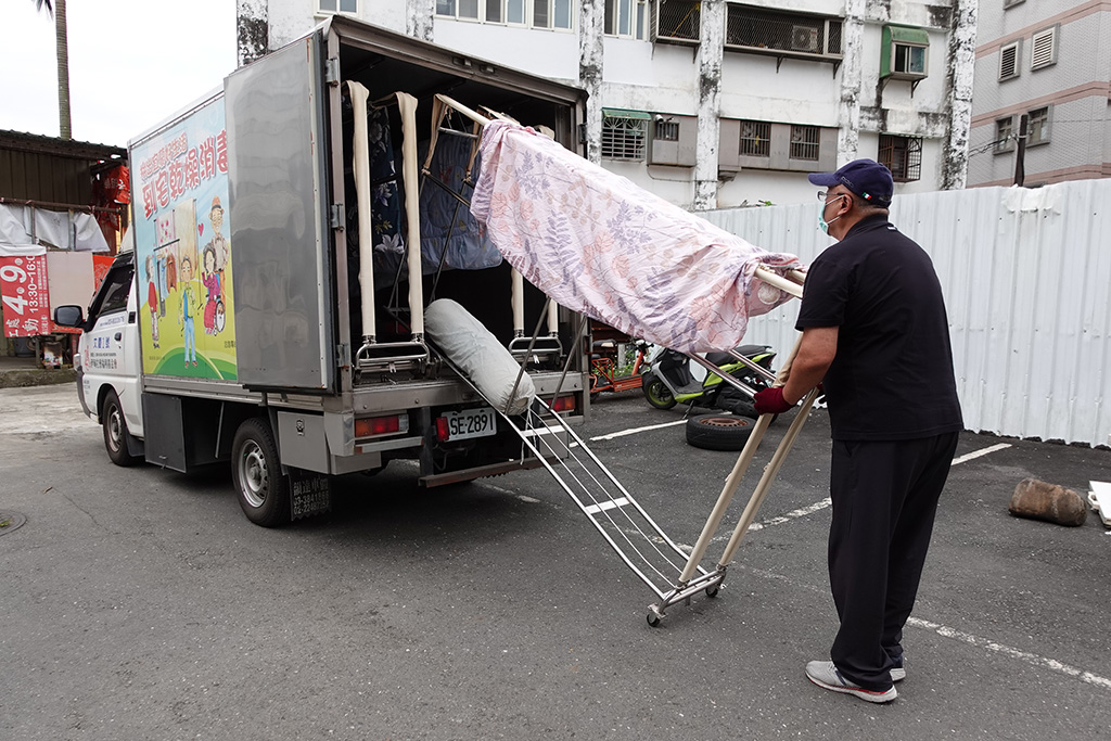 伊甸宜蘭乾燥消毒車操作人員將案家的被單與衣服上架，進行除濕、消毒與烘乾等清潔工作。