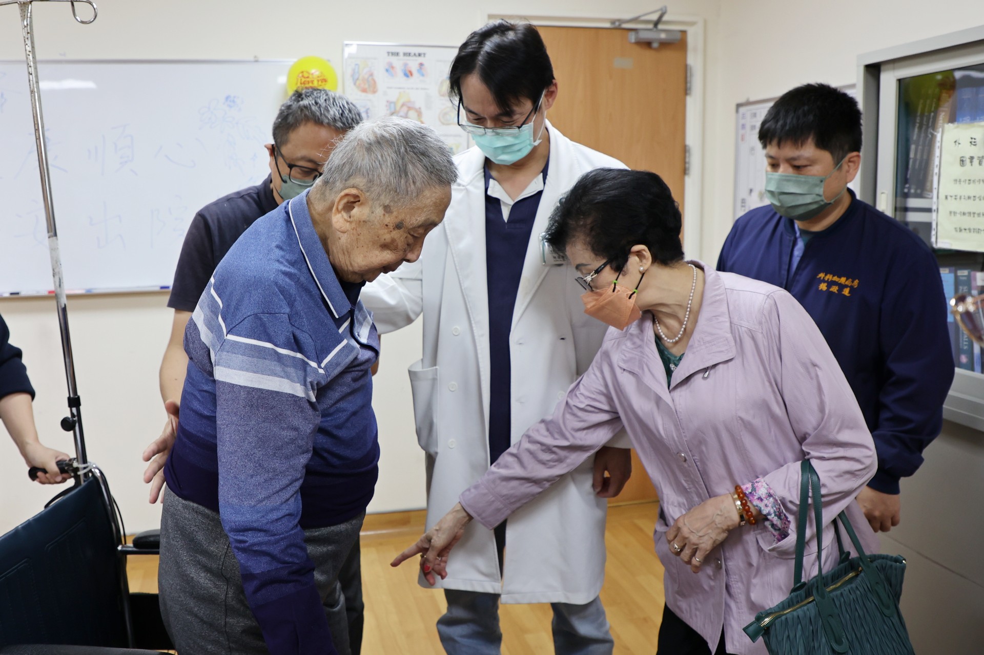 吳阿公(左)迫不及待與重症加護外科主任何冠進(中)分享可以短站站起的喜悅。