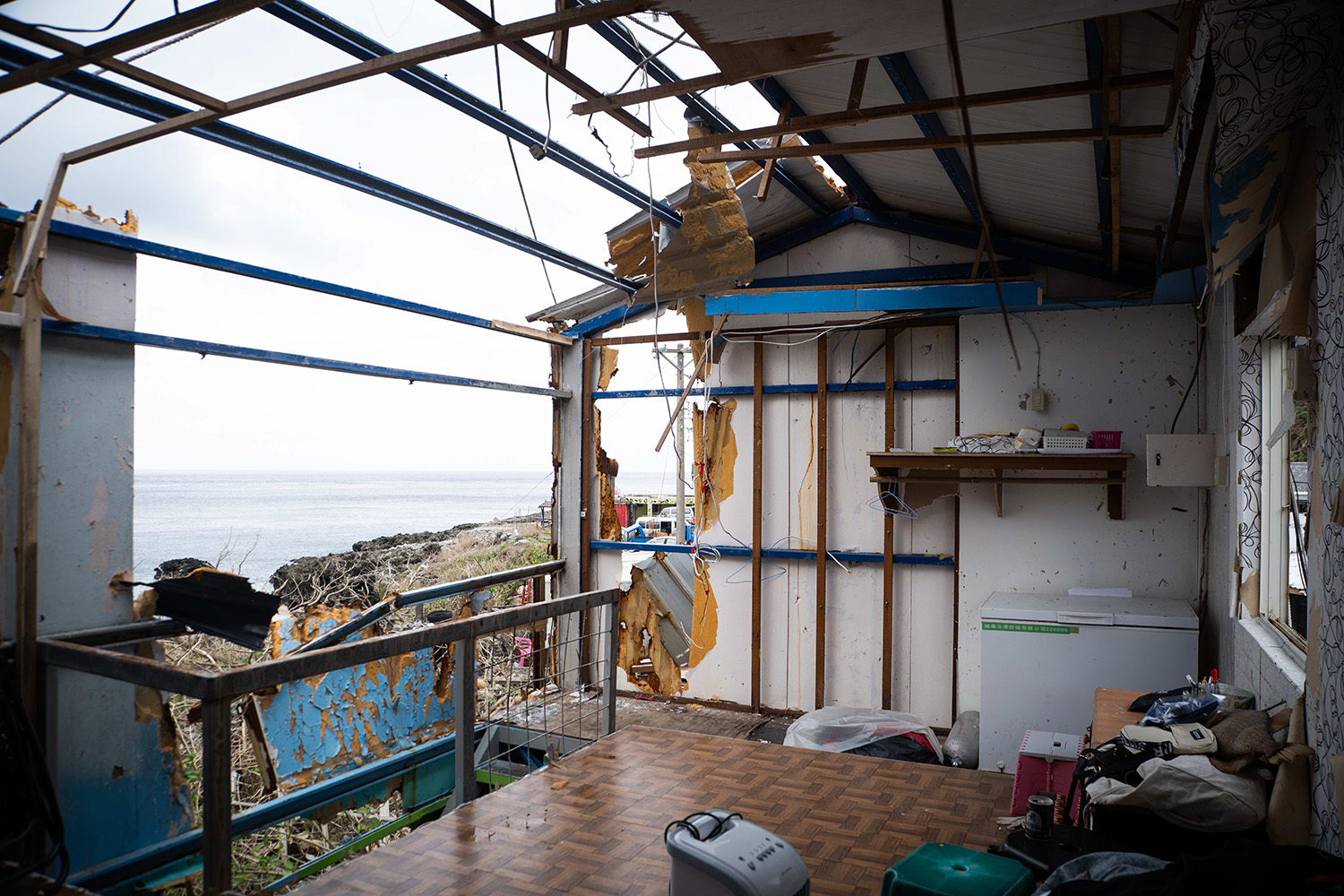 小妮家裡開的海濱小餐廳二樓屋頂和牆面被颱風掀掉，媽媽沒辦法再做小生意為生，面臨遙遙無期的修建之路 (台灣世界展望會提供)  