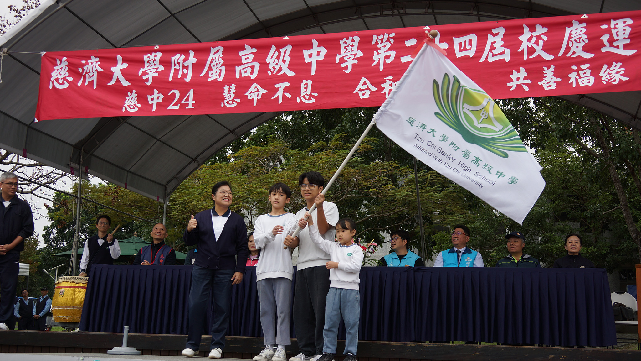 李玲惠校長授旗予中學部班聯會會長李研頡、小學部環保小局長魯期禮及幼兒園石若彤
