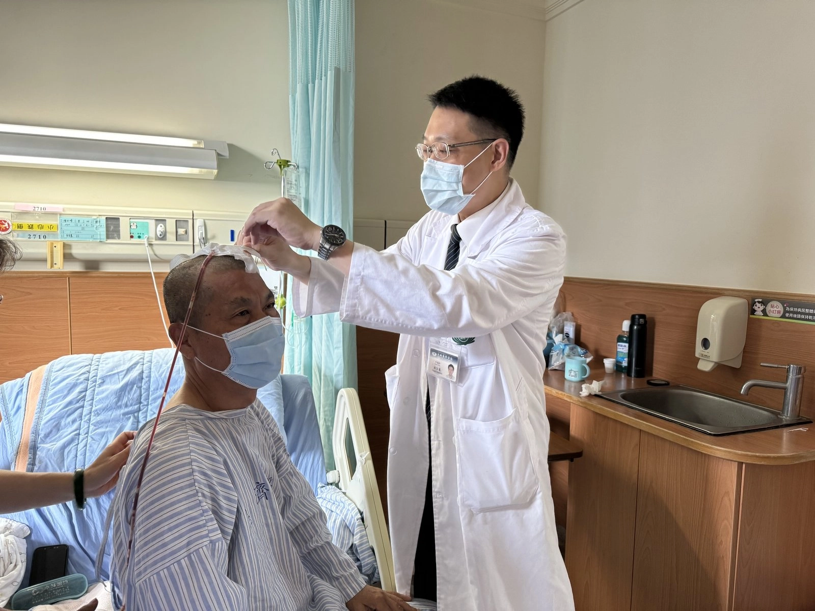 神經外科吳宗憲醫師為陳先生手術治療後，查看置入引流管狀況