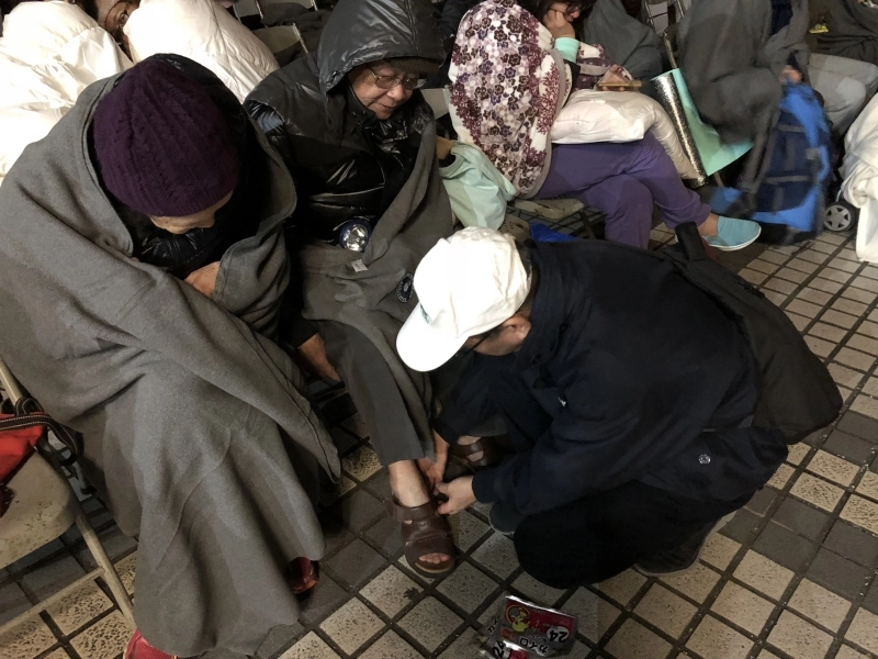 2月6日花蓮強震，慈濟志工關懷撤離民眾，何日生在第一時間即時趕到現場，為長者置放暖暖包於鞋中，讓手腳增添暖意。