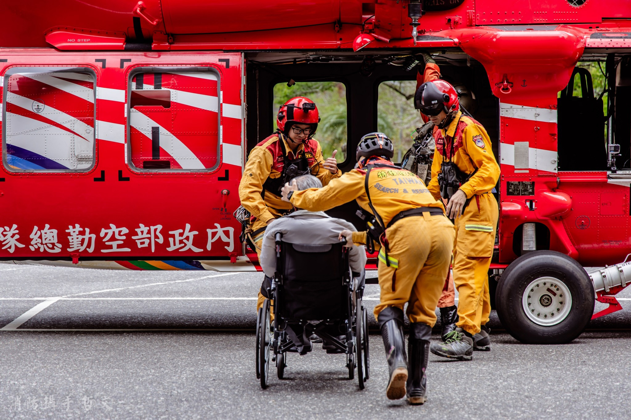 搜救隊員向坐輪椅的脫困民眾比讚手勢，代表對受困民眾表達平安的祝福。