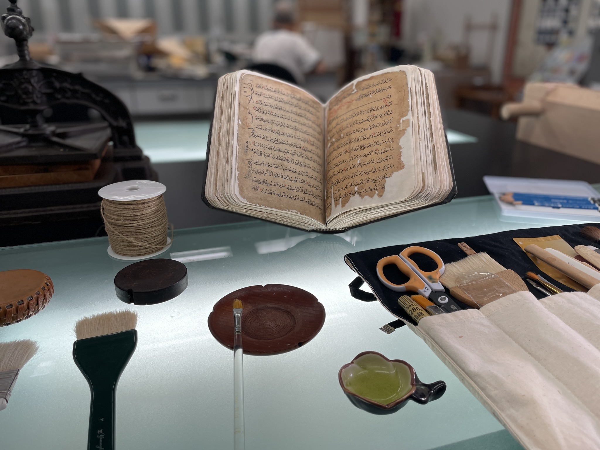 俢復後的百年古蘭經與修復師的工具。
