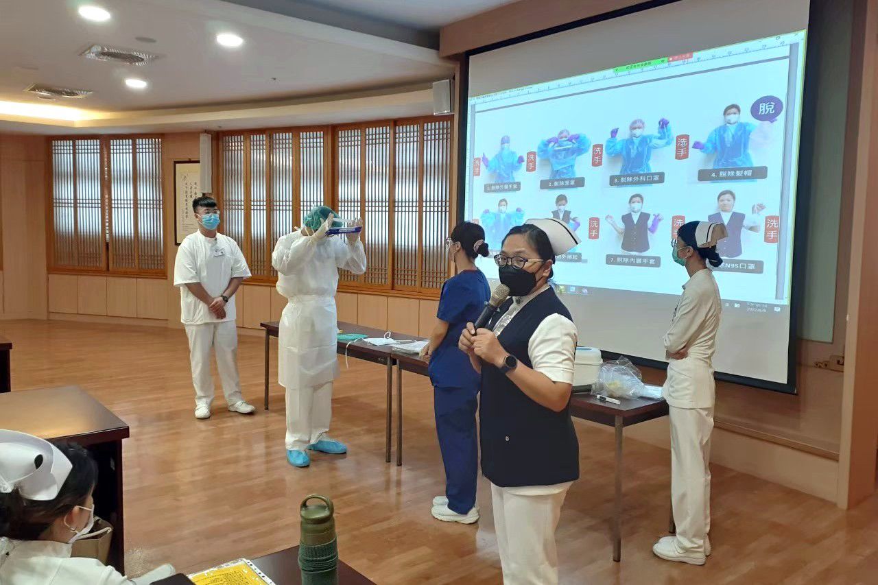 江如萍護理長於新人訓練課程(右二)指導學生正確穿脫防護衣。