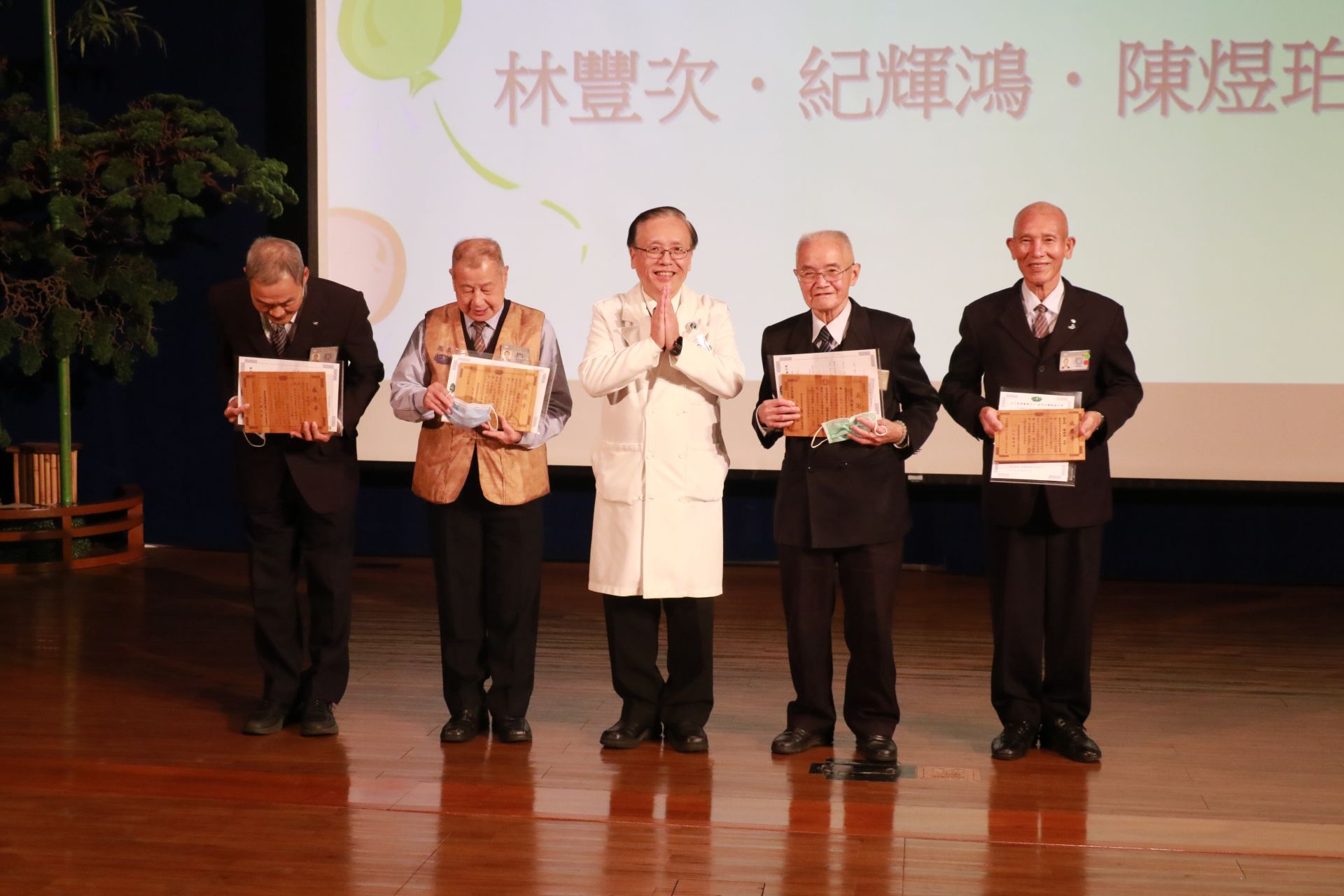 簡守信院長和志工時數達五千小時的四位志工合影。